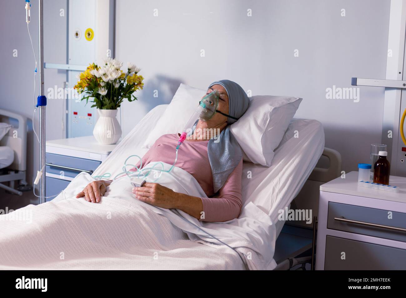 Senior caucasian female cancer patient wearing head scarf in bed with