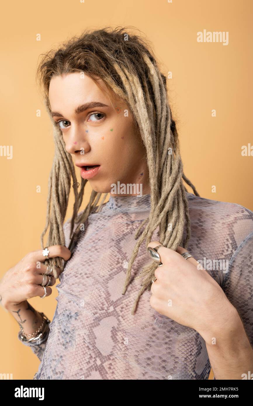 Nonbinary person touching dreadlocks and looking at camera isolated on yellow,stock image Stock Photo