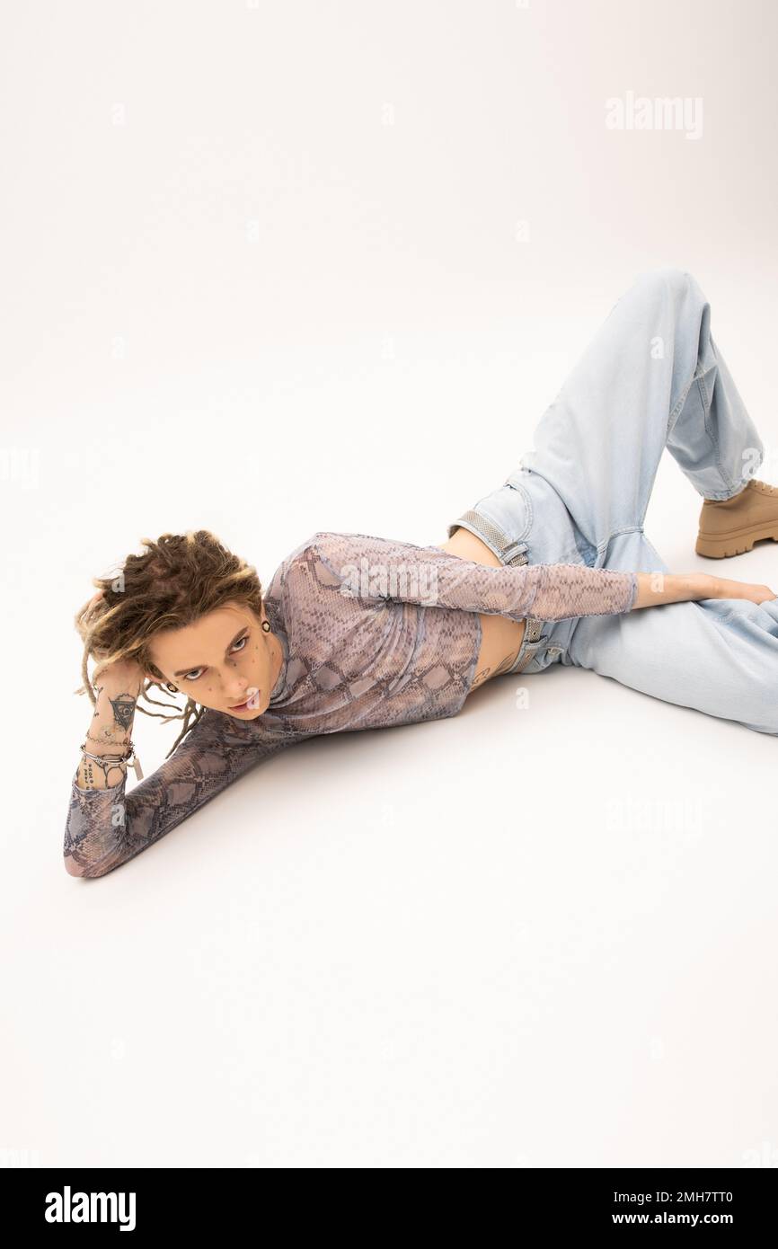 Queer person with dreadlocks lying on white background,stock image Stock Photo
