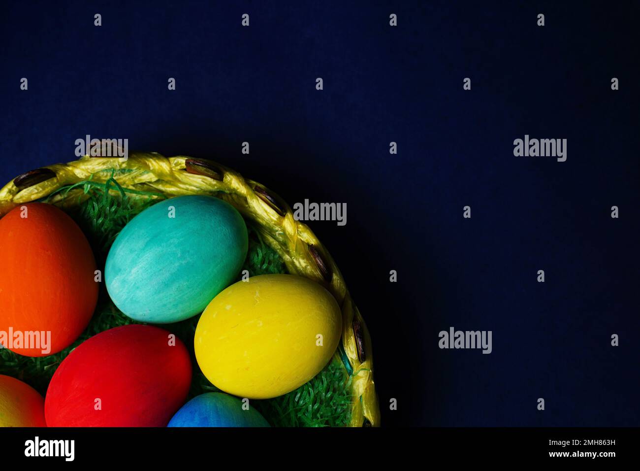 Easter composition with colorful eggs in basket on blue background. Stock Photo