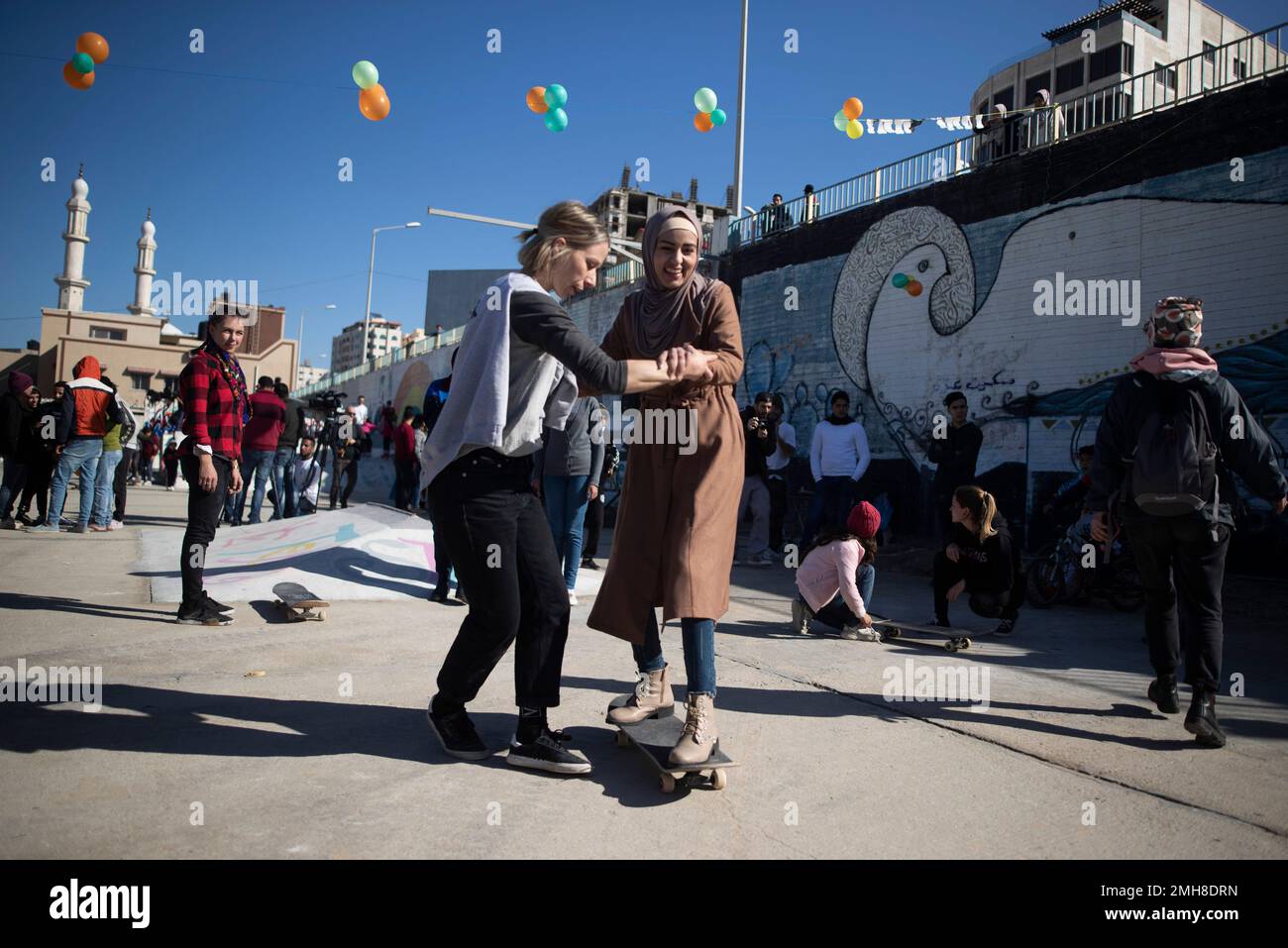 An Italian activist trains skateboarding to a young Palestinian, at an ...