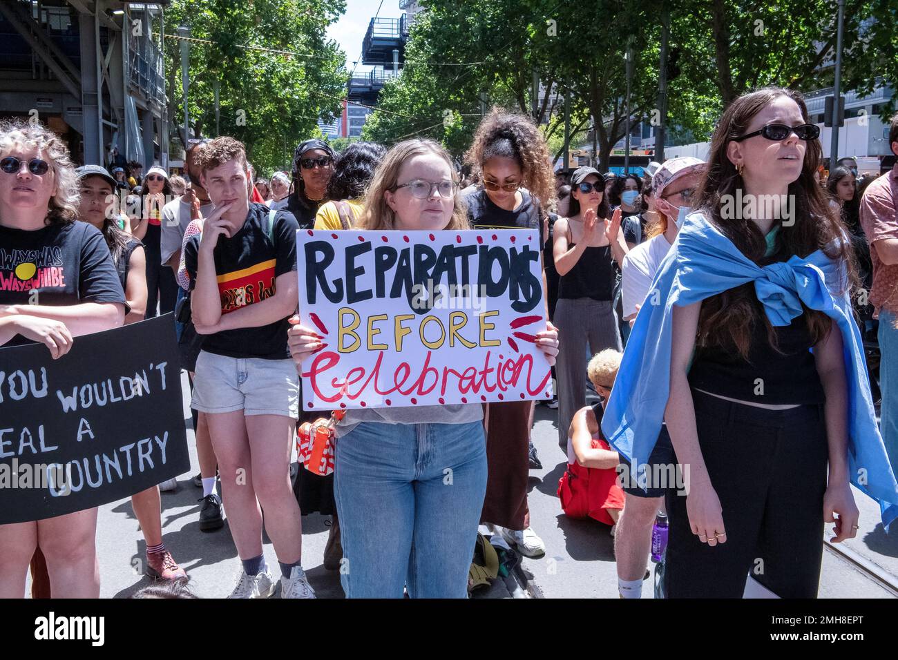 Melbourne, Australia, 26 January, 2023. A female protester with a sign 'reparations' before celebrations' during the annual Invasion Day protest in Melbourne, organized by Indigenous Australians and their allies, calls for an end to the celebration of Australia Day and for the recognition of Indigenous sovereignty. Credit: Michael Currie/Speed Media/Alamy Live News Stock Photo