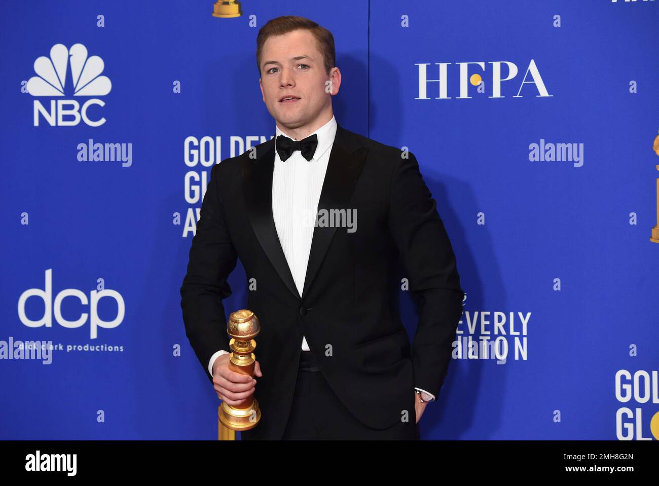Taron Egerton poses in the press room with the award for best