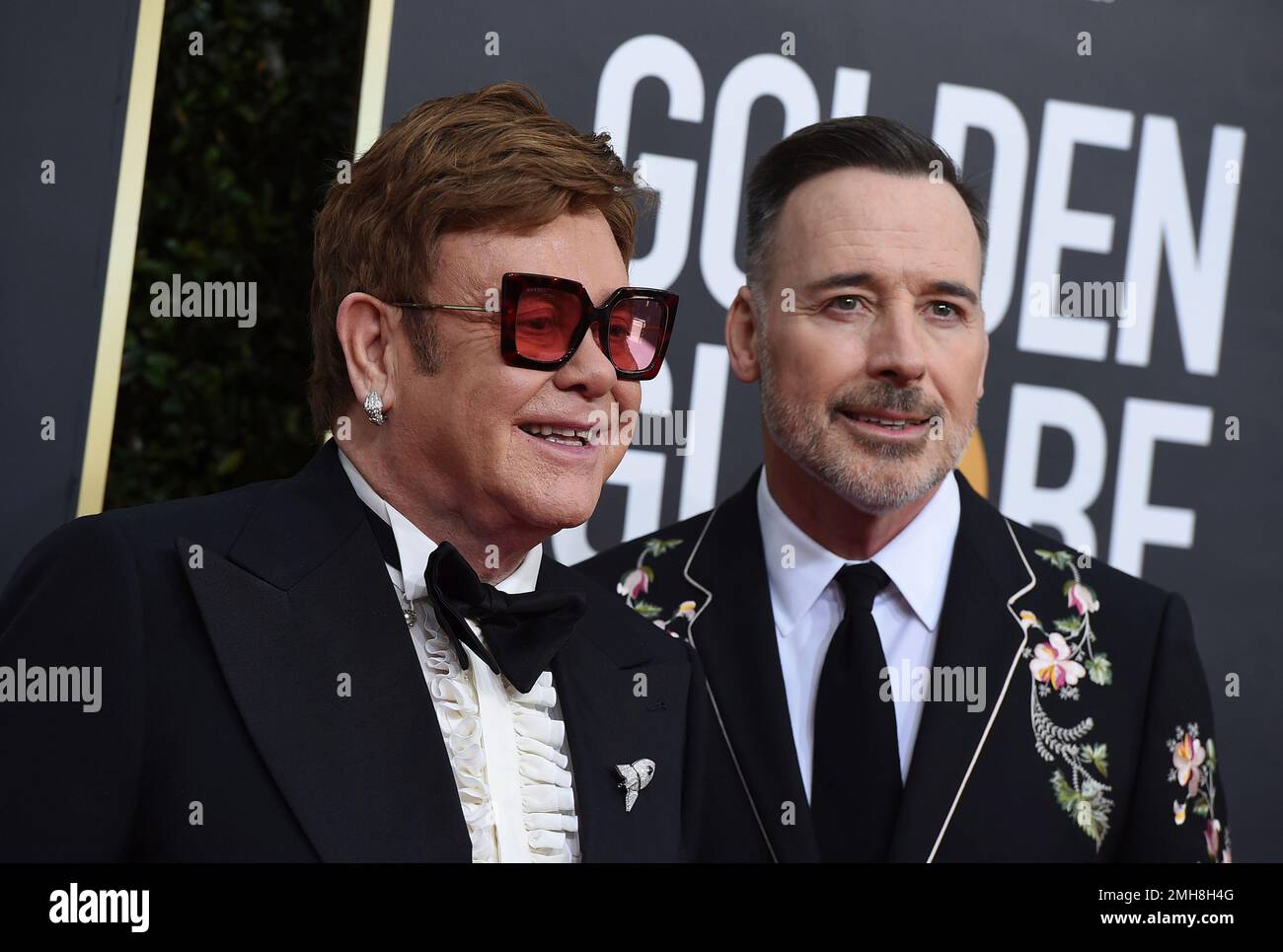 Elton John, left, and David Furnish arrive at the 77th annual Golden