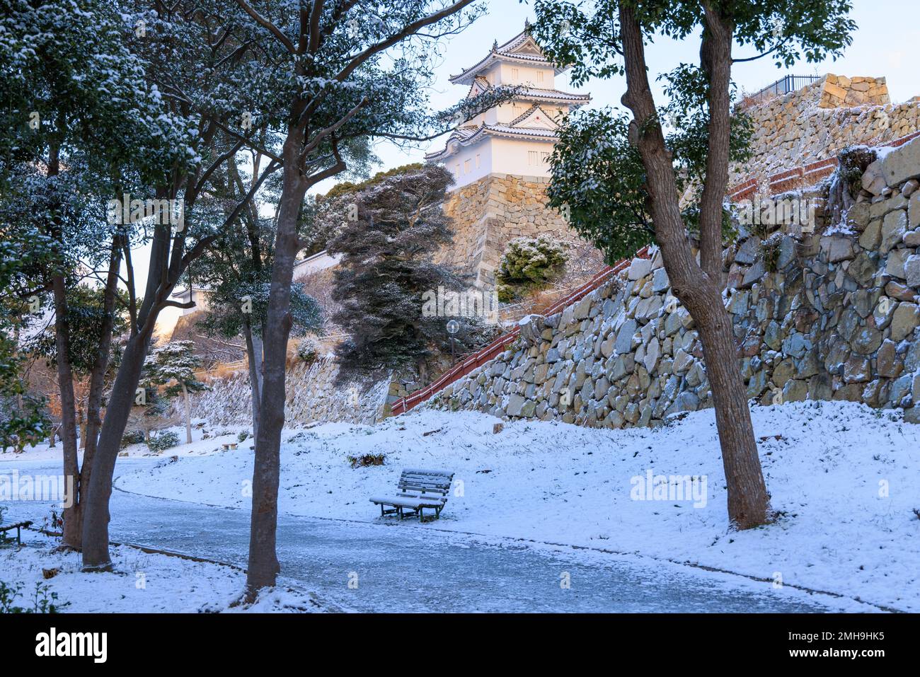 Snow covered bench at Japanese castle park on winter day Stock Photo