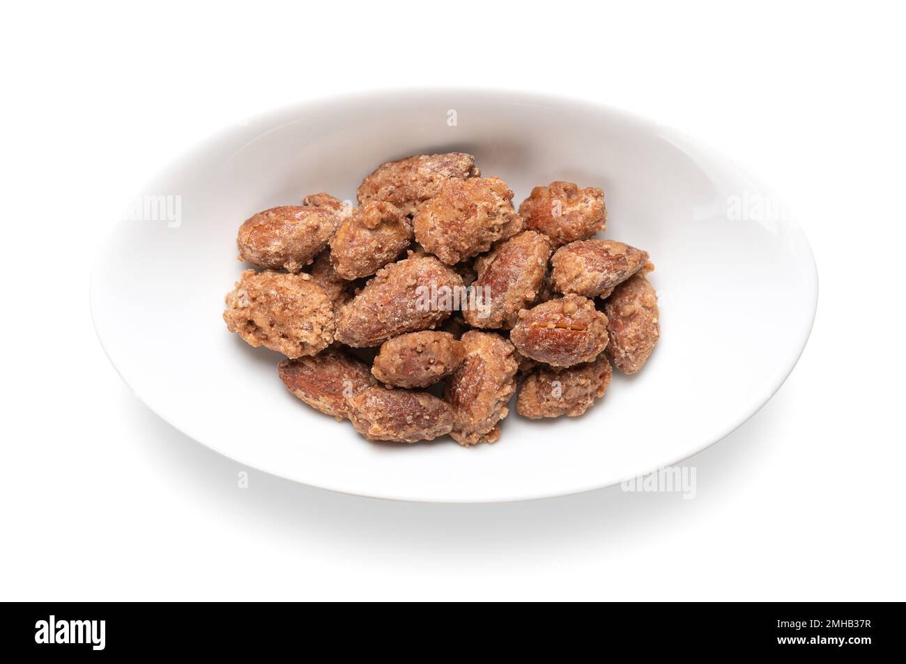 Candied almonds in an oval white bowl. Homemade, in a special way cooked almonds, whole nuts coated in crunchy sugar. Sold at Christmas markets. Stock Photo