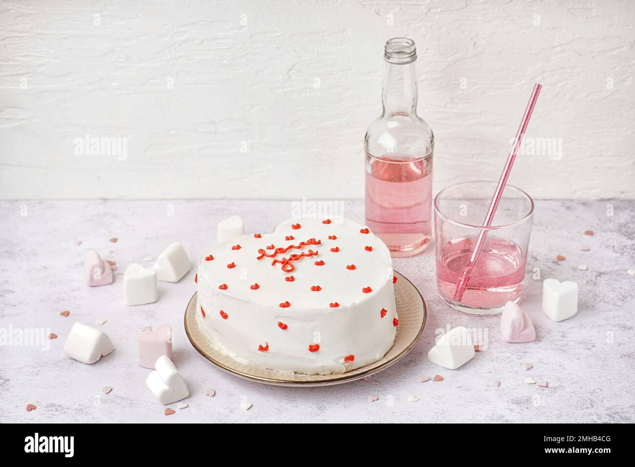 Plate with heart-shaped bento cake, bottle and glass of tasty drink on ...