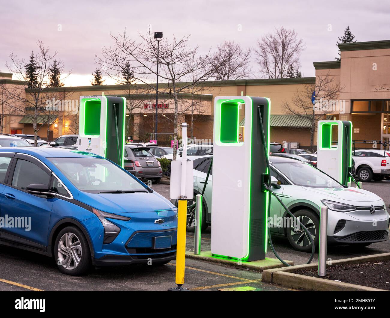 Electric car charging stations glow at dusk in a shopping mall parking lot.  Bellingham WA, USA. Stock Photo