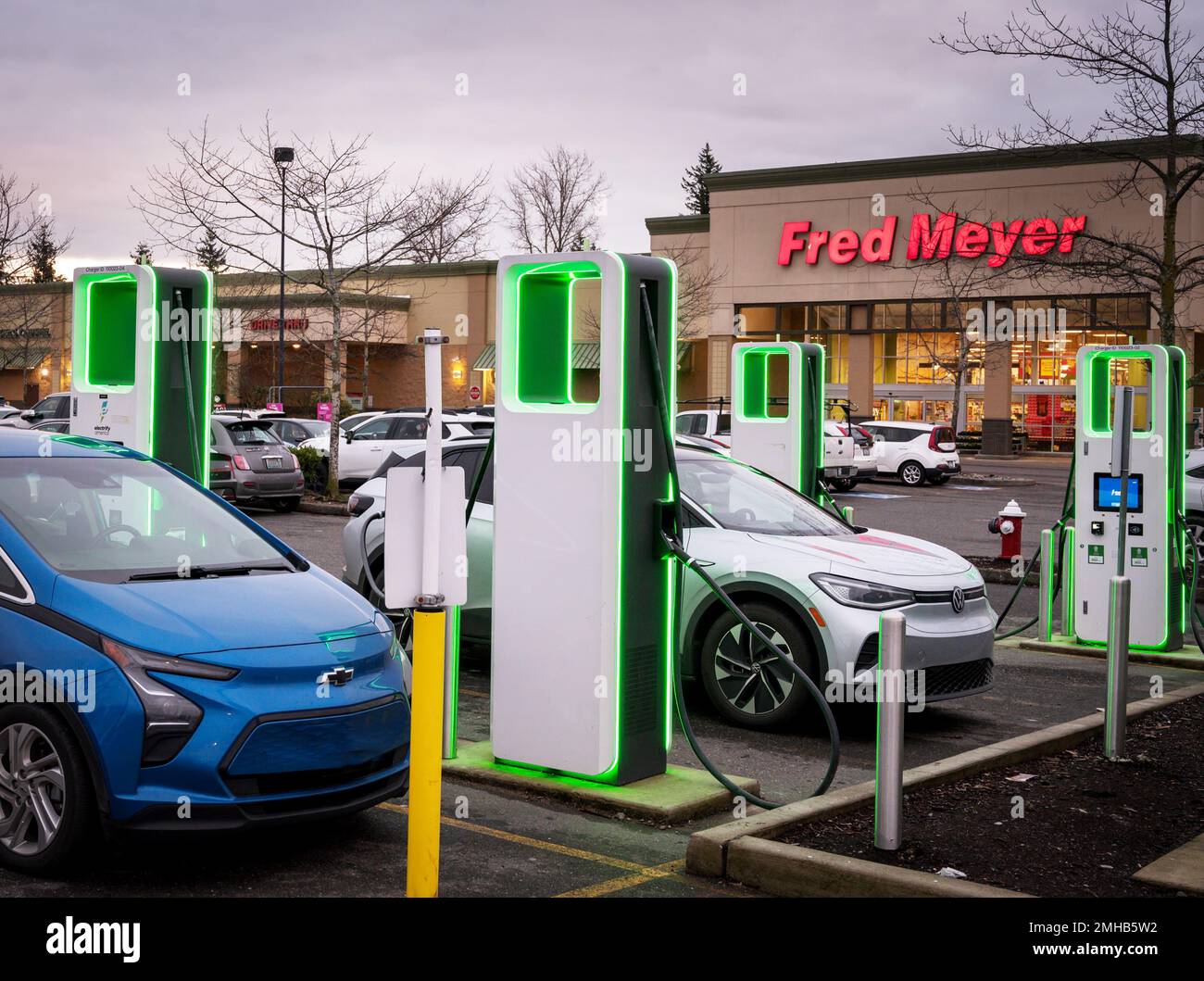 Electric car charging stations glow at dusk in a shopping mall parking
