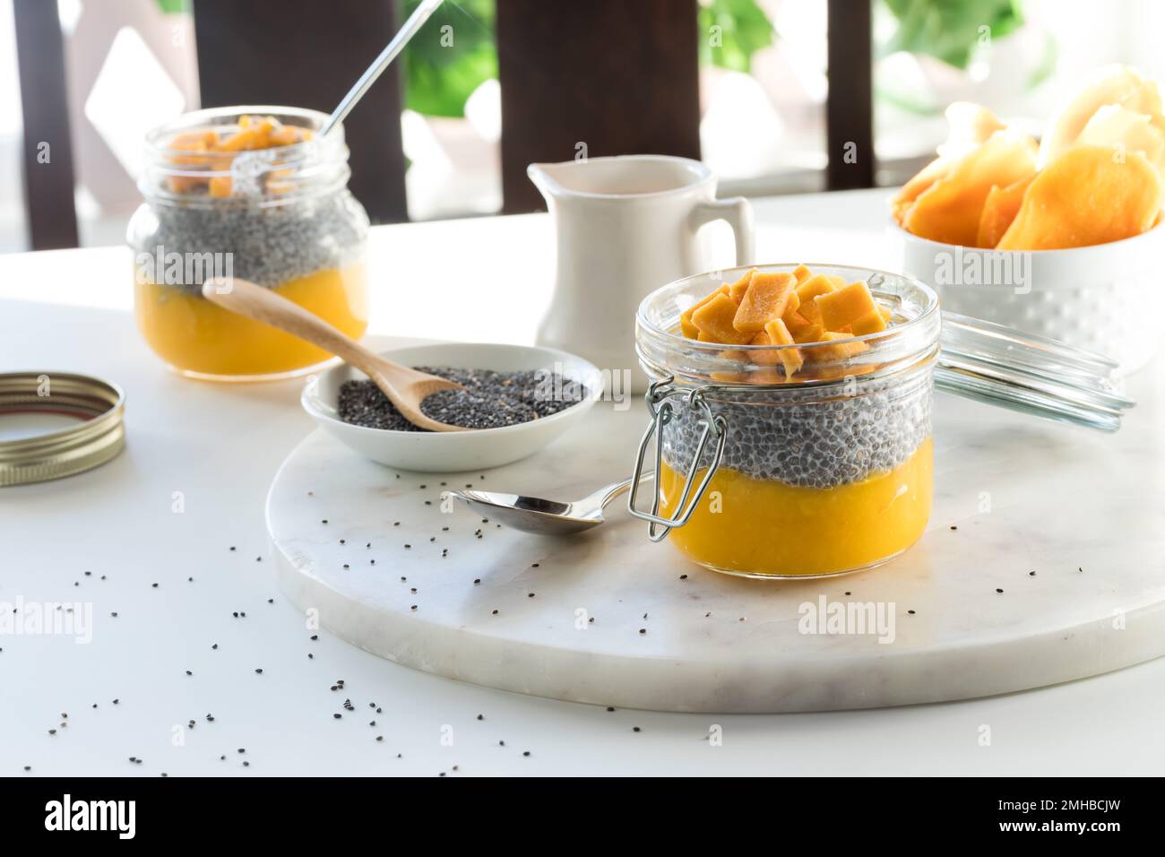 Mango chia pudding snacks on a table with bright sunlight in behind. Stock Photo