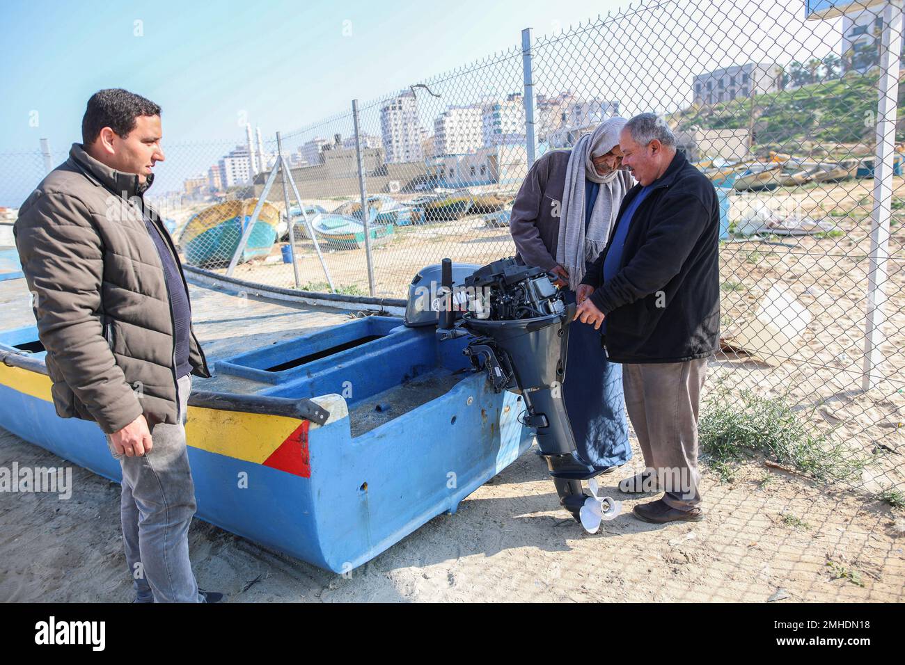 A local technical worker stands with a Palestinian fisherman near his fishing boat after installing a new engine on it at the Gaza seaport in Gaza City. In the last week, permitted the import of 12 outboard engines, said the United Nations. Israel had previously barred their entry based on concern they could prove 'dual use'. The repairs are taking place at an U.N.-supervised workshop on the beach, near the so-called 'Boat Graveyard' where dozens of rusty vessels have been piled up, abandoned after breakdowns. (Photo by Ahmed Zakot/SOPA Images/Sipa USA) Stock Photo