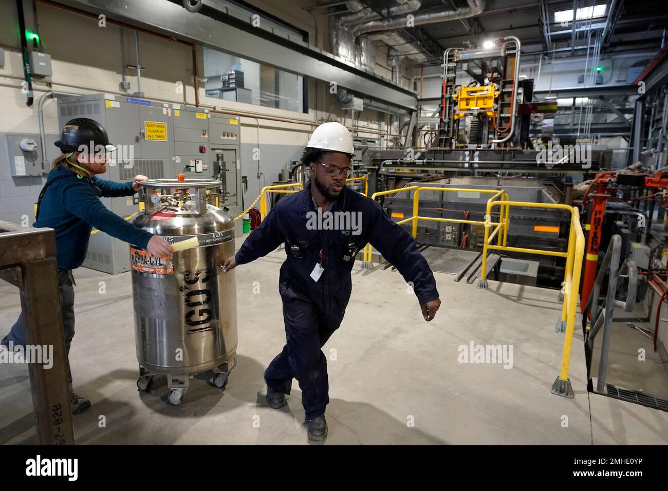 Workers transport equipment past a semiindustrial electrolytic cell