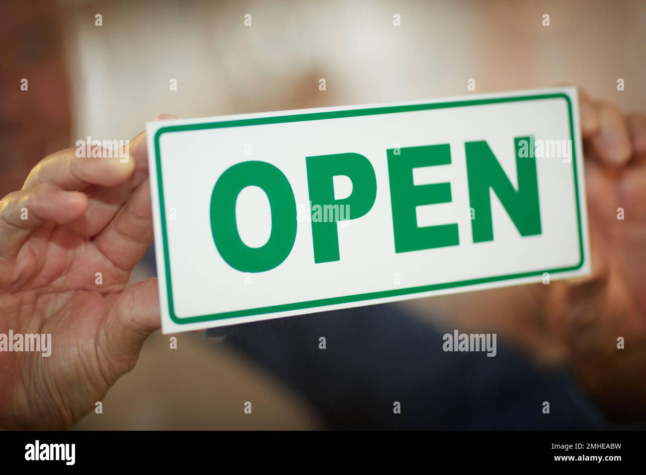 Come on in. an unidentifiable business owner holding up and open sign