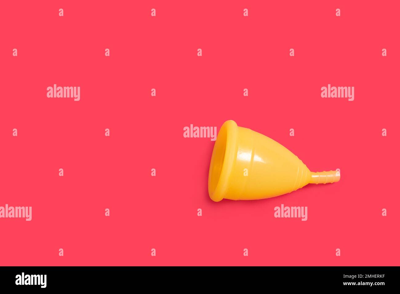 Yellow menstrual cup isolated on red background. Women's health concept
