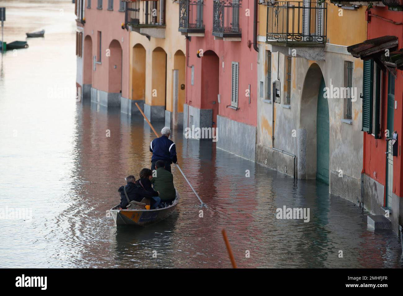 People stand on a boat as water reaches the houses after the Ticino river  overflowed its banks, in Pavia, Italy, Monday, Nov. 25, 2019. Officially  say at least seven people died as