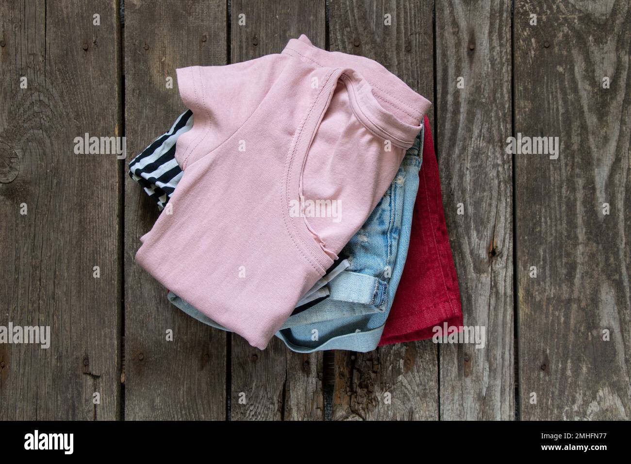 womens t-shirt and denim shorts lay on rustic brown background, womens clothing, fashion, many womens things Stock Photo