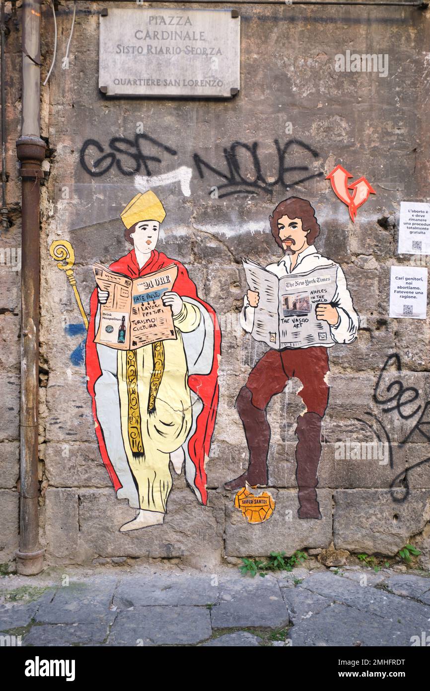 Two paper posters, depicting Saint Gennaro and artist Caravaggio, both reading newspapers. An example of graffiti in Naples, Napoli, Italy, Italia. Stock Photo