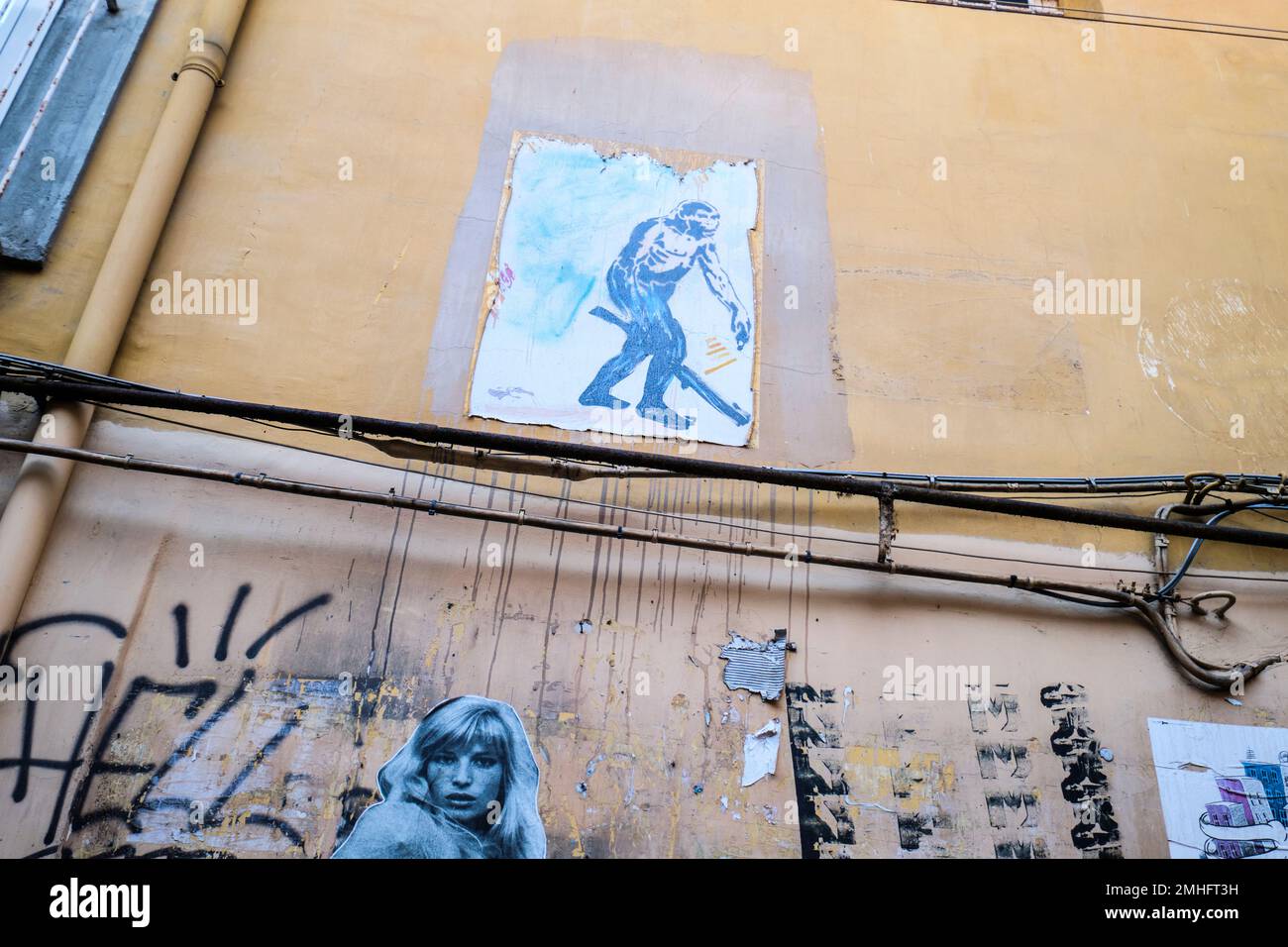 A sticker stencil of a stone age cave man, walking with a large stick, club. Actress Monica Vitti is below. An example of grafitti in Naples, Napoli, Stock Photo