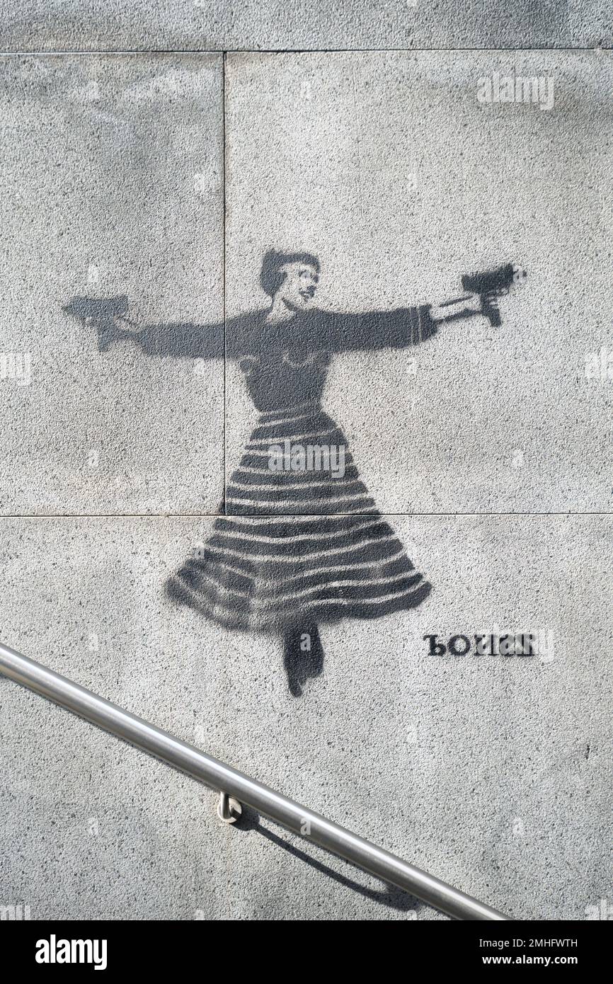 A painted stencil by the artist Bones of Julie Andrews from the Sound of Music, holding two Uzi submachine guns. At a Metro station stop entrance. An Stock Photo