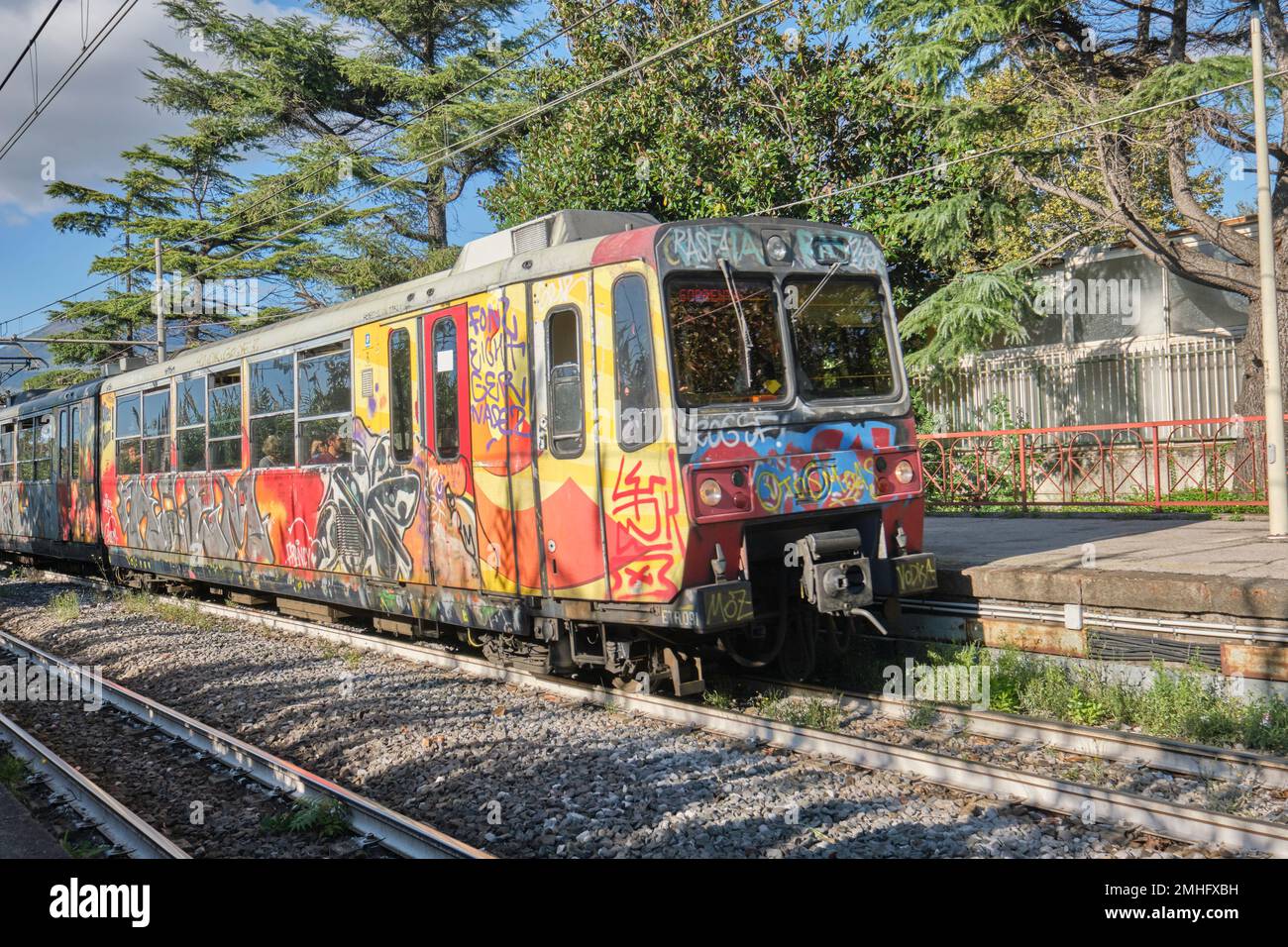 A grafitti covered commuter train pulling into a rail station near Pompeii. An example of graffiti in Naples, Napoli, Italy, Italia. Stock Photo