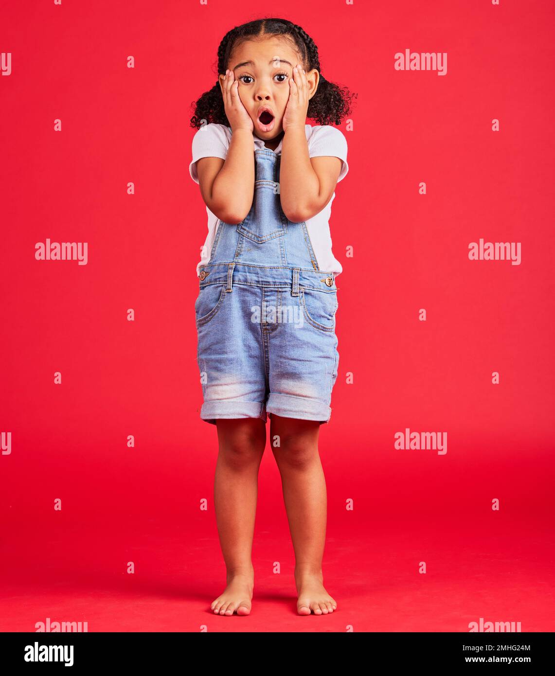 Child portrait, shocked or hands on face by isolated red background in kids gossip, bad news or scary children story. Surprised, anxiety or scared Stock Photo