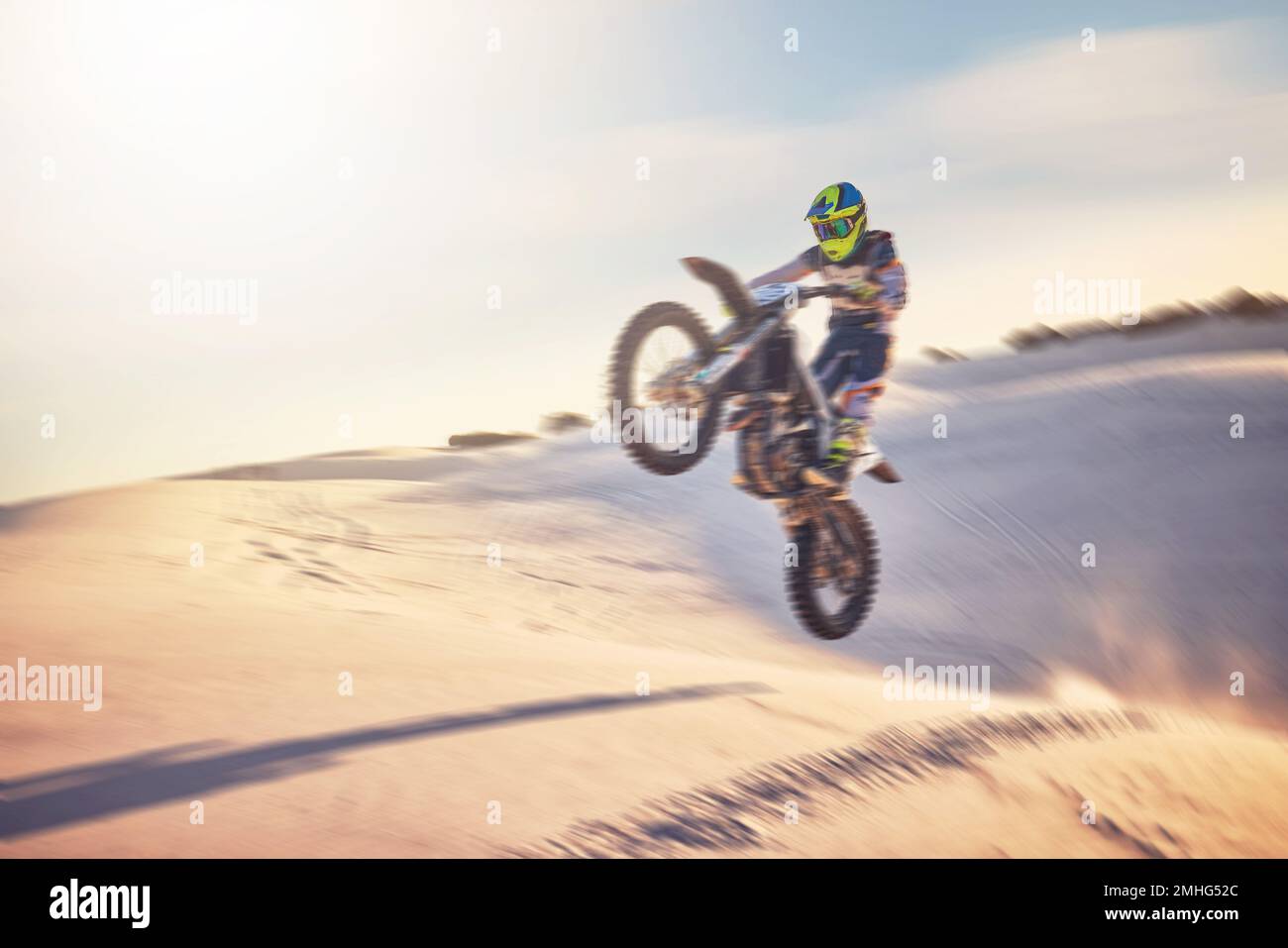 Motorcycle, athlete and sports outdoor with jump stunt, fitness in desert and extreme sport with speed and freedom. Challenge, power and biking with Stock Photo