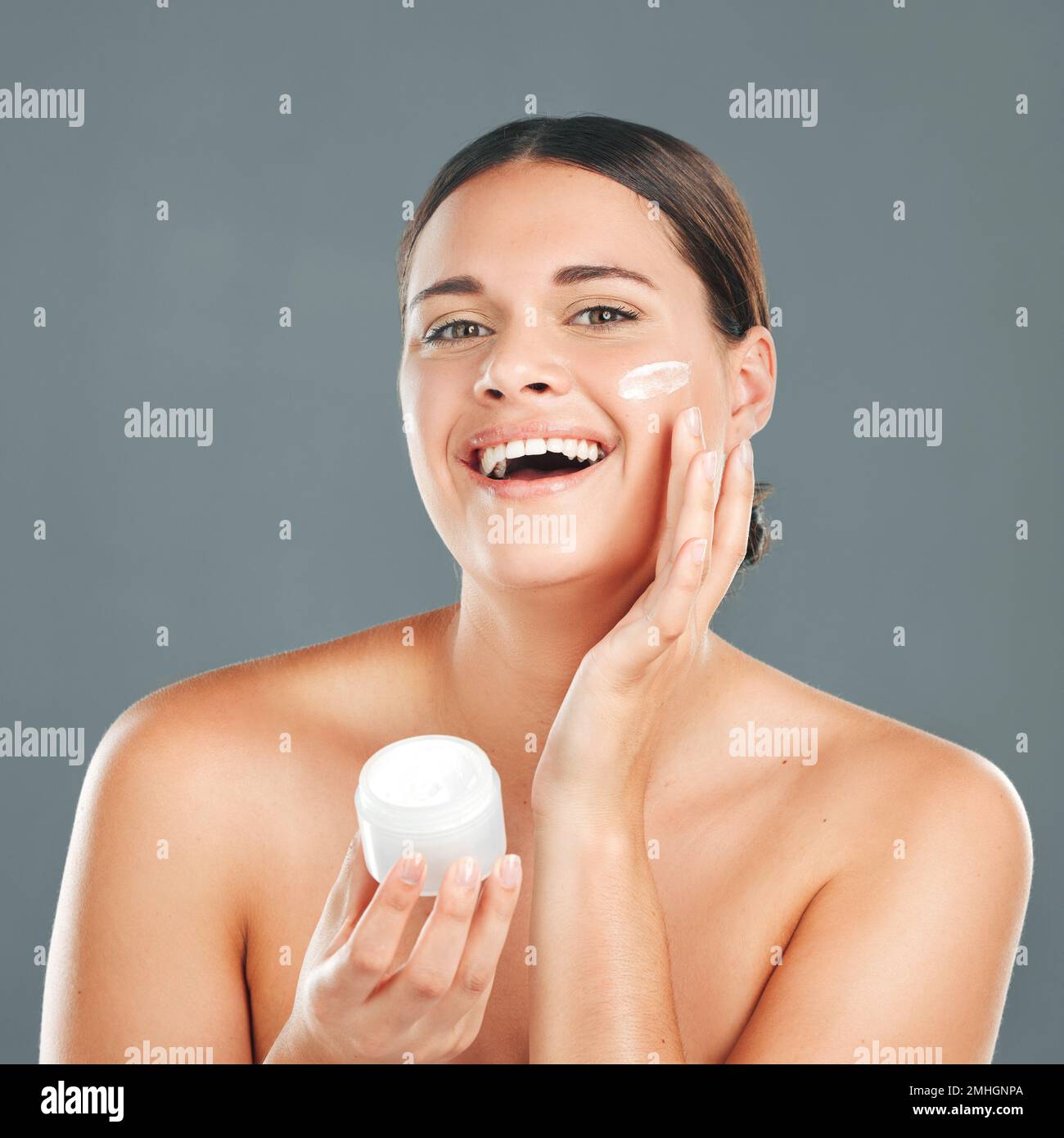 Woman apply cream for face, happy in portrait and beauty, skincare and moisturizer isolated on studio background. Sunscreen, lotion and healthy skin Stock Photo