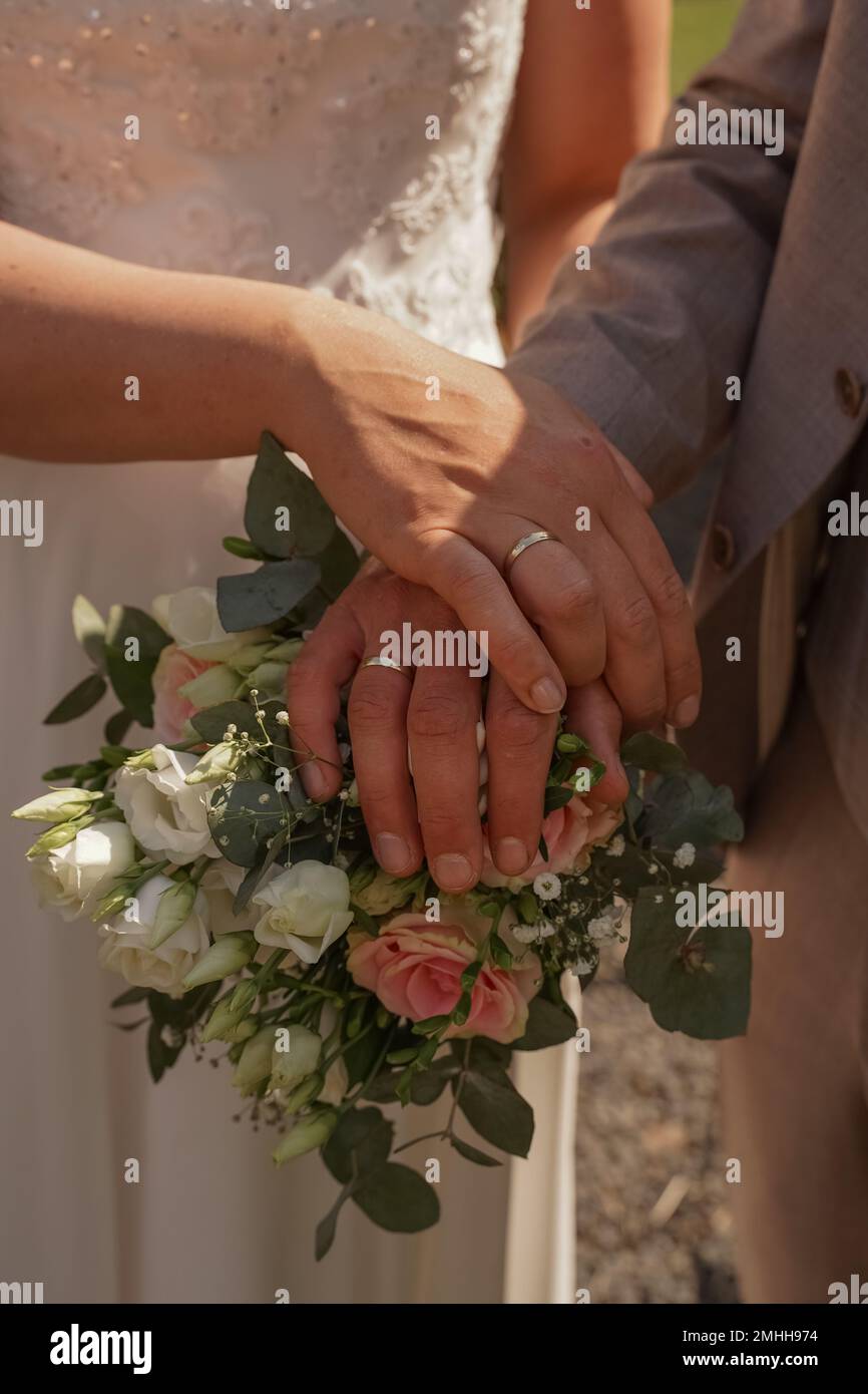 Hands of the bride and groom on the wedding bouquet Stock Photo - Alamy