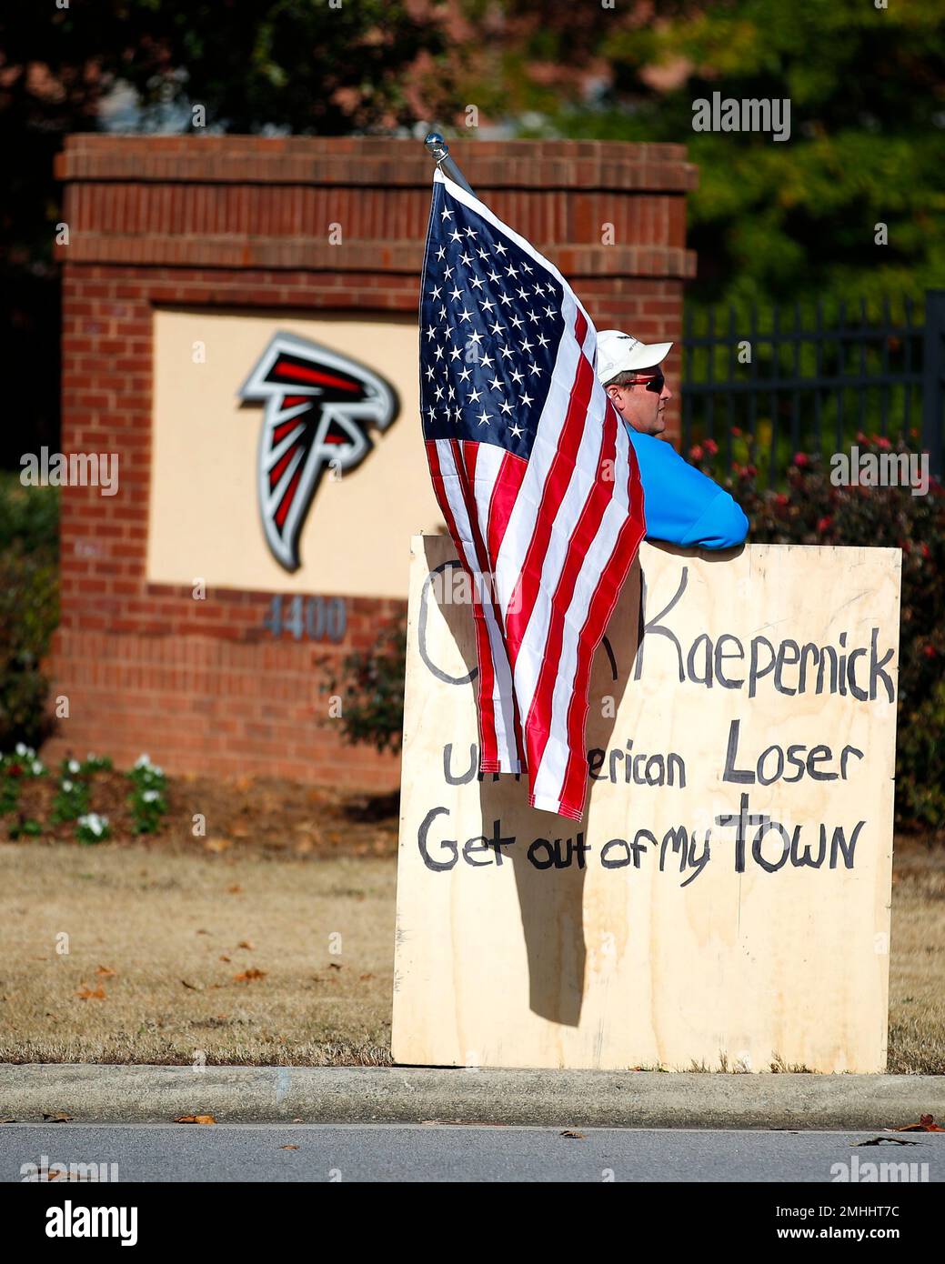 A protester holds an American flag and a sign outside of the Atlanta  Falcons' training facility where free agent quarterback Colin Kaepernick  was set to workout for NFL football scouts, Saturday, Nov.