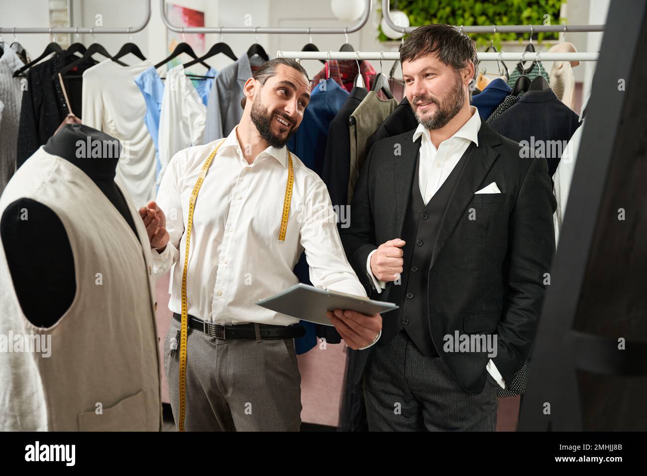 Cheerful tailor communicating with client in his atelier Stock Photo
