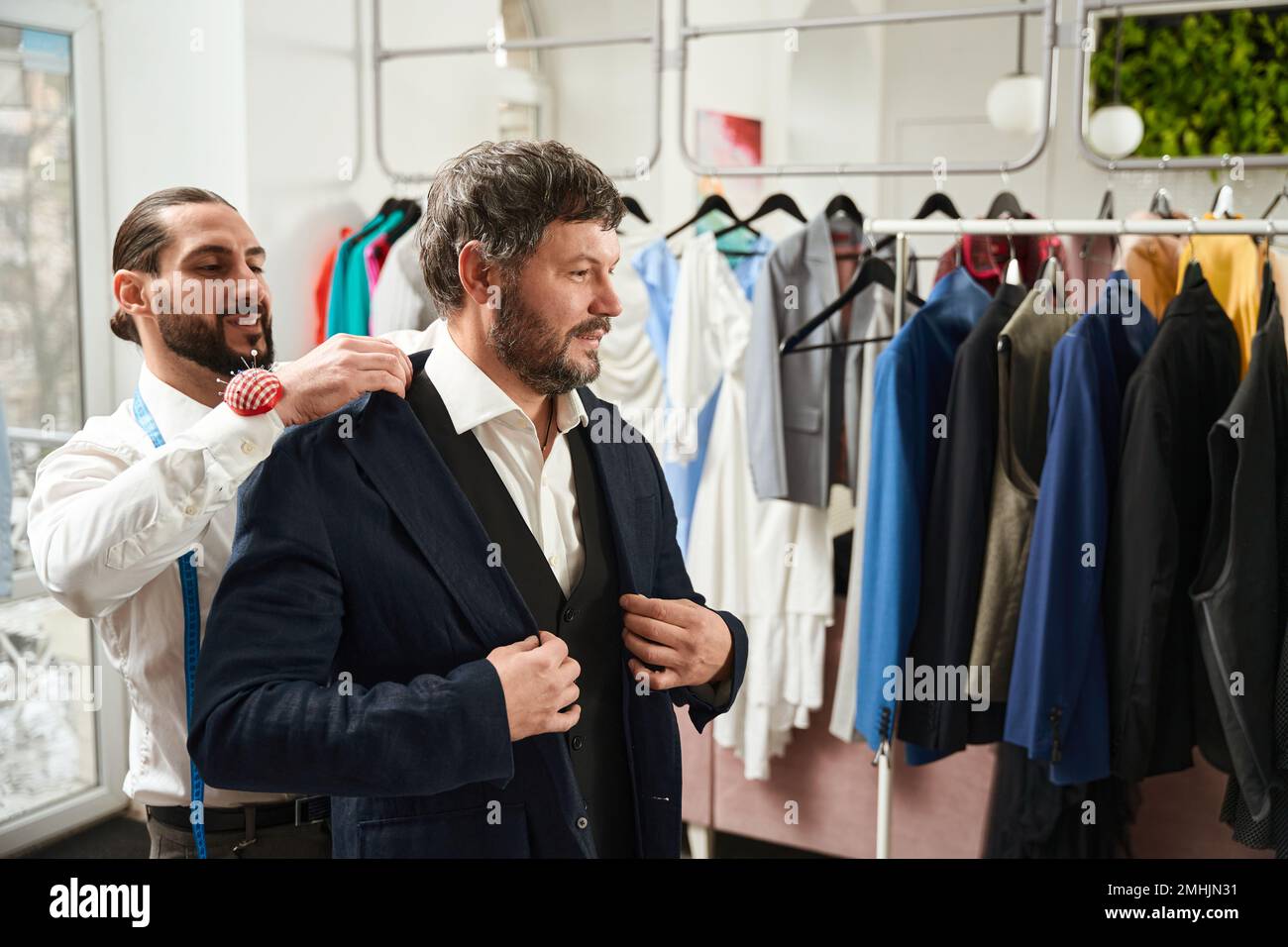 Joyous tailor checking fit of jacket on gentleman Stock Photo - Alamy