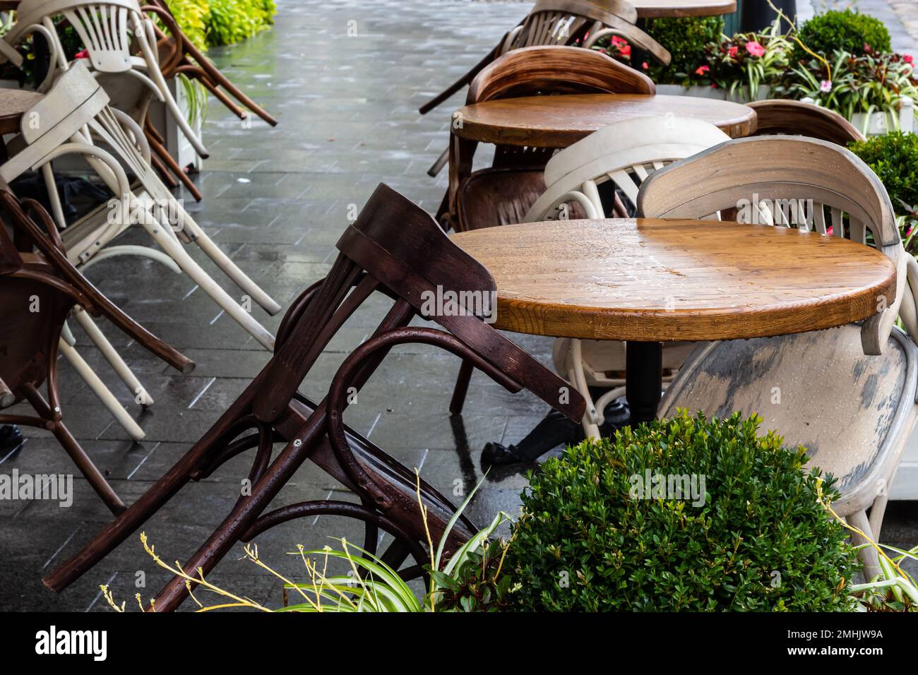 Empty wet wooden table and chairs on terrace of outdoor cafeteria
