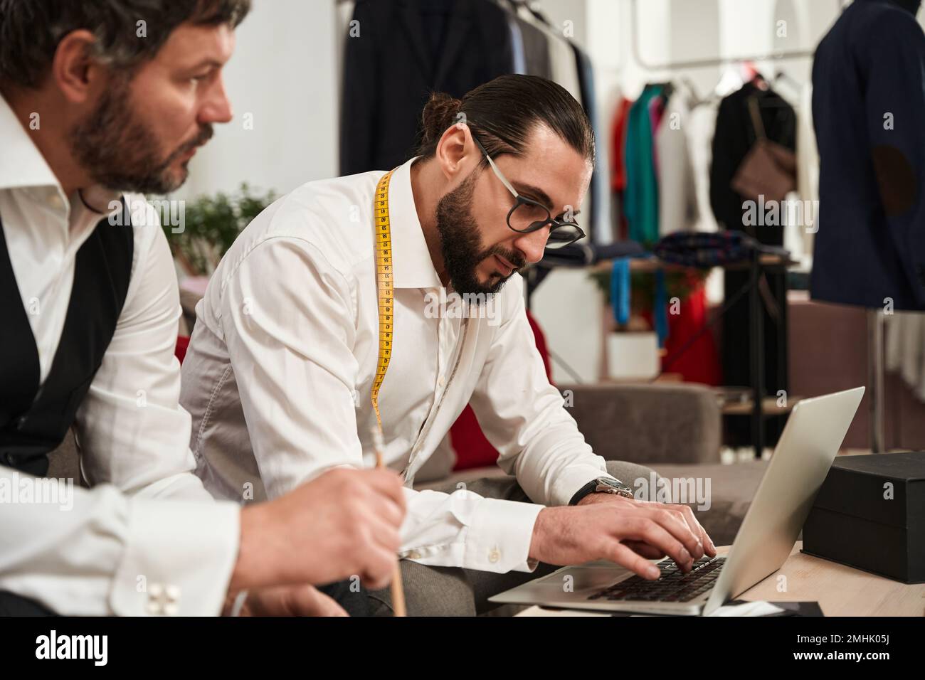 Two modern clothiers using laptop in atelier Stock Photo