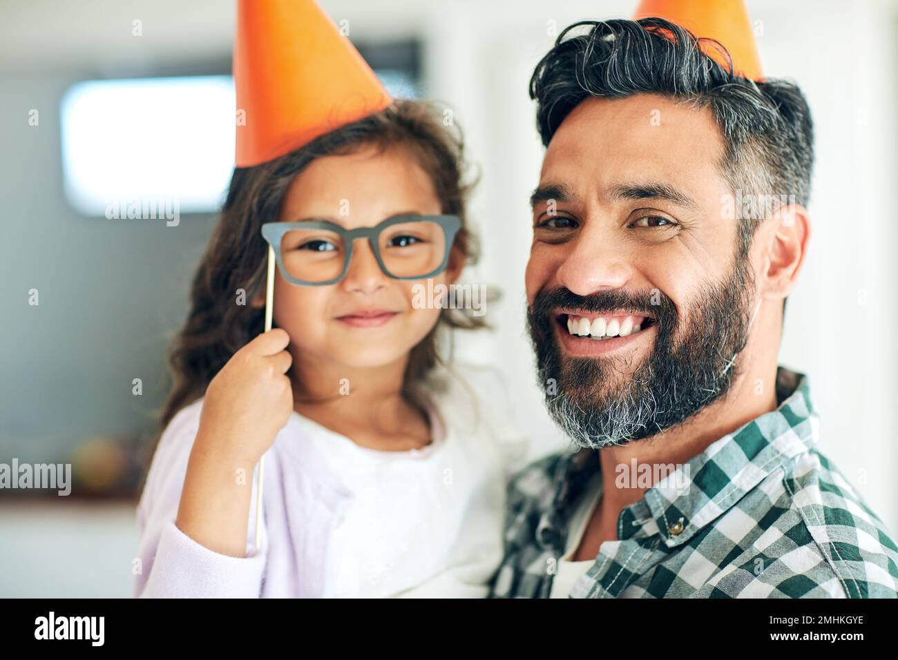 Shes my clever little cutie. Portrait of a cute little girl and her father playing with dress-up props at home. Stock Photo