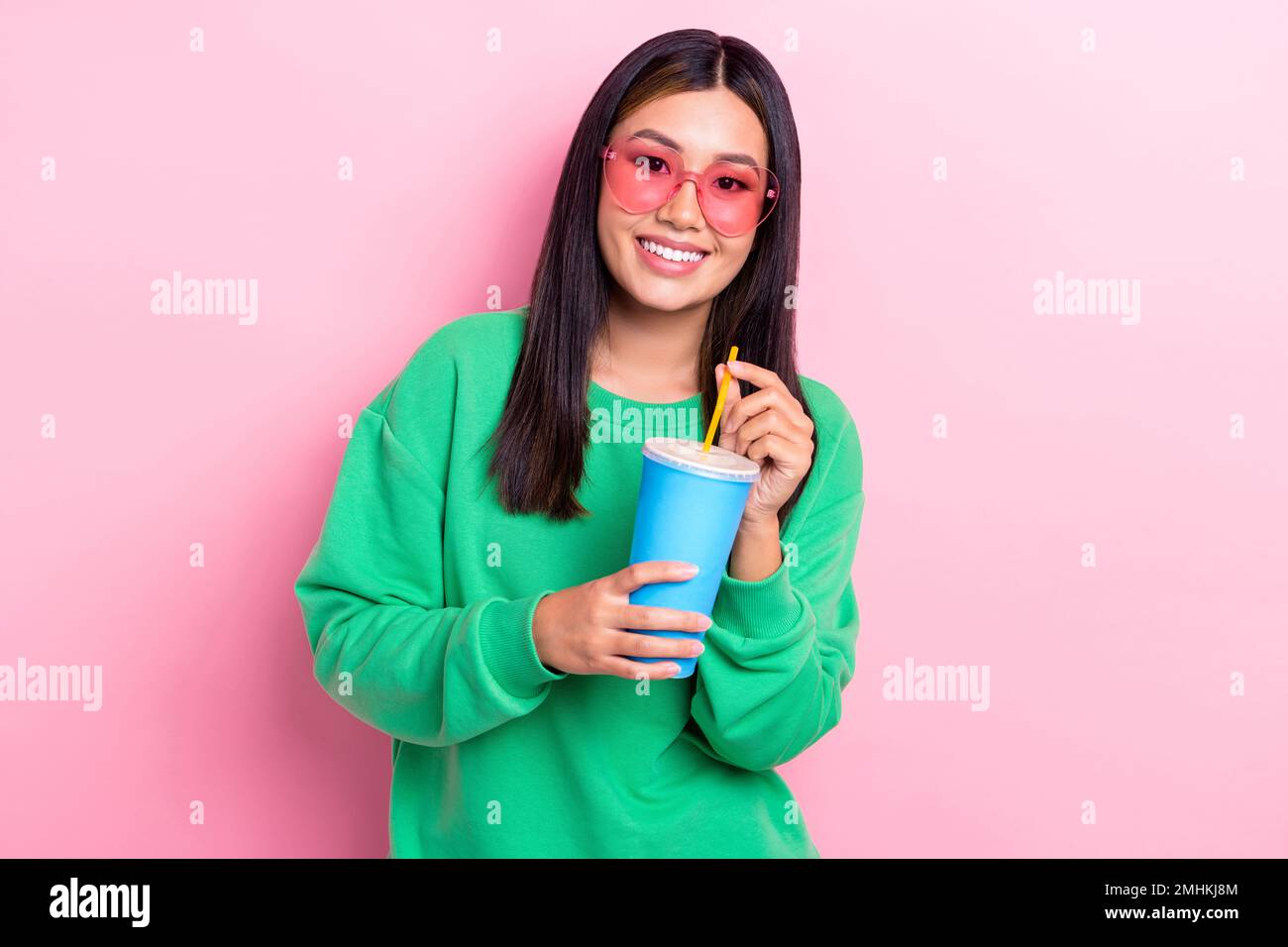Portrait of positive cute thai girl toothy smile hands hold plastic drink cup isolated on pink color background Stock Photo