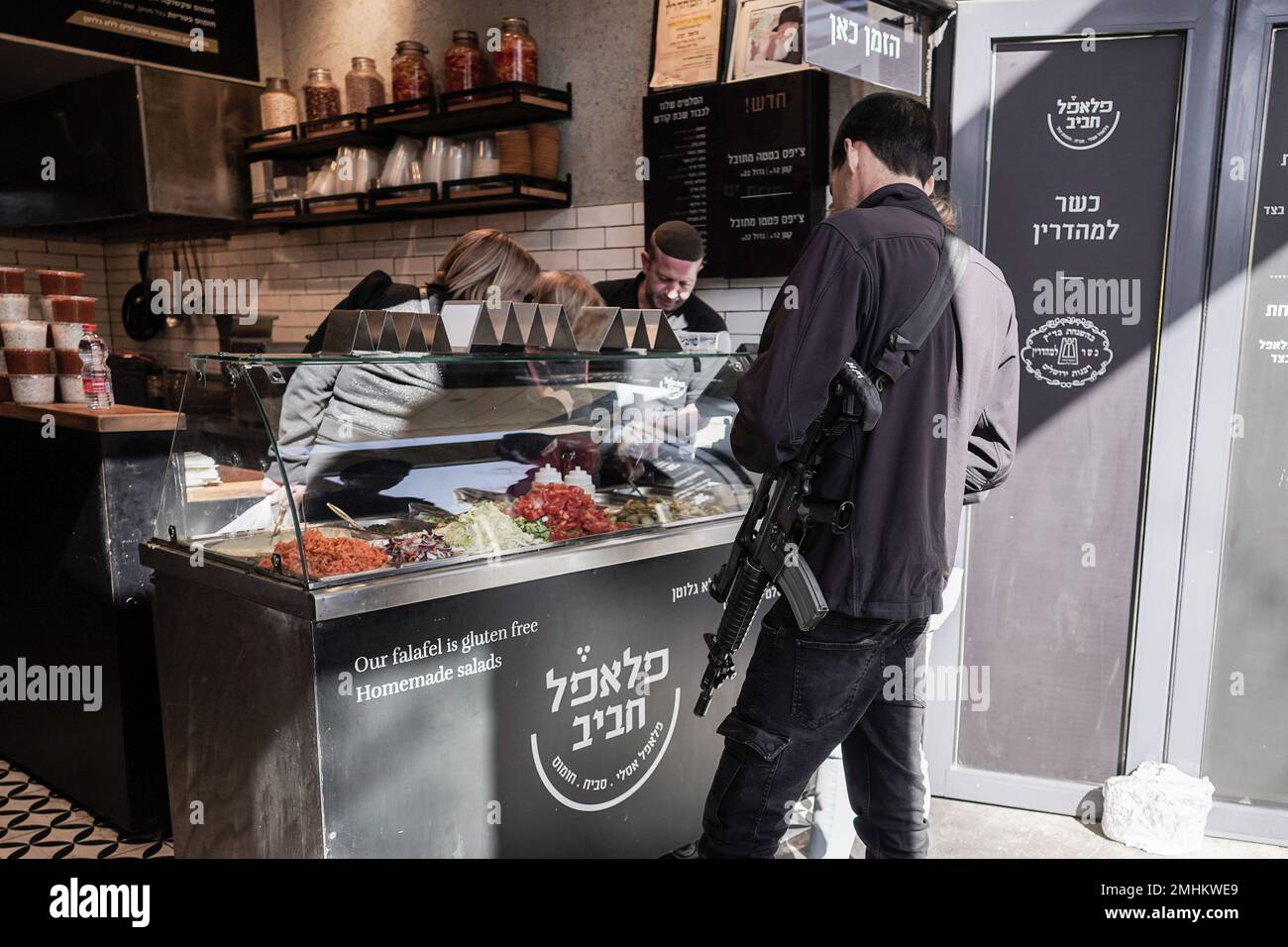 Jerusalem, Israel. 27th Jan, 2023. An off duty IDF officer carries an M16 while buying falafel. Credit: Nir Alon/Alamy Live News Stock Photo