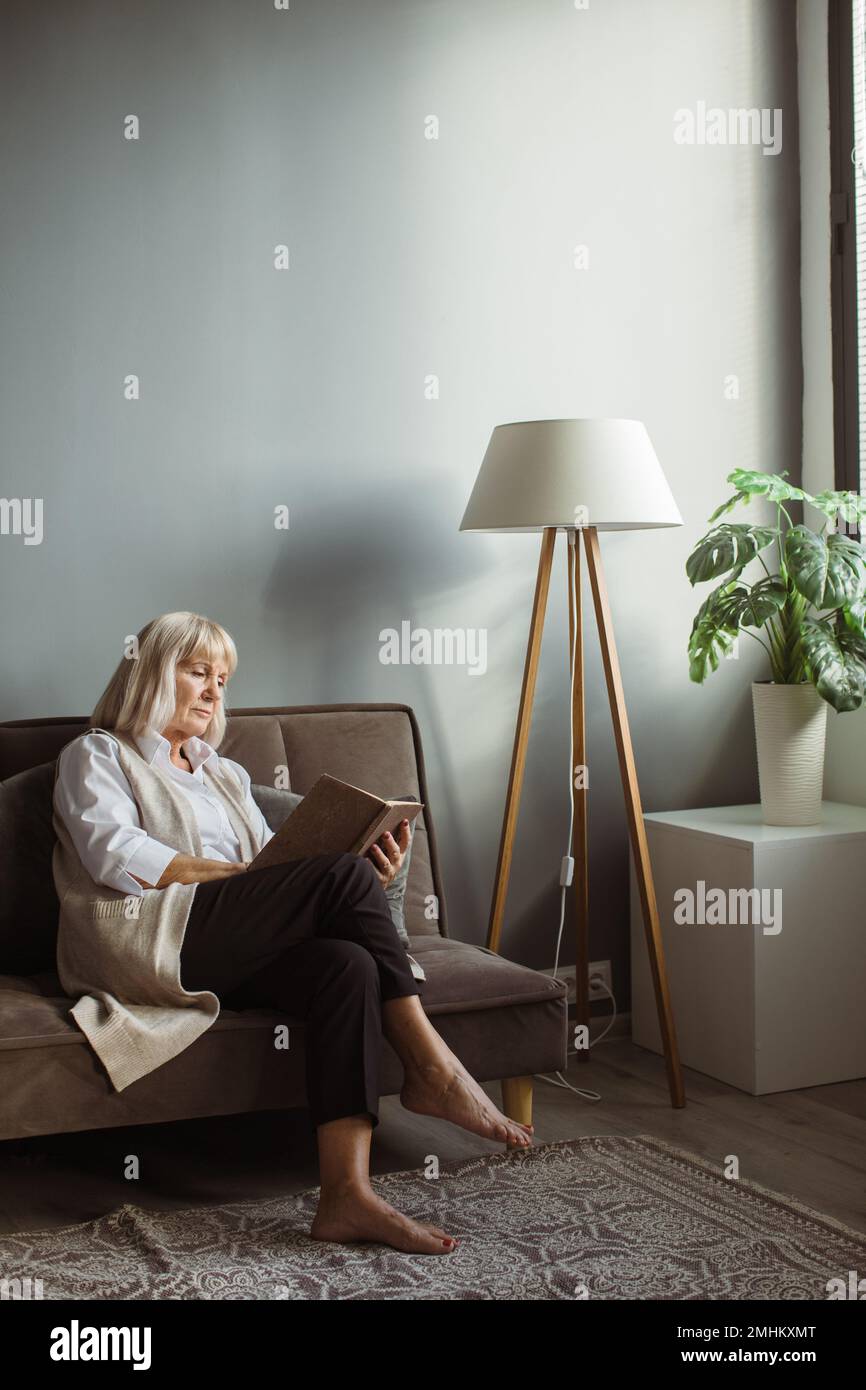 Mature woman sitting on sofa hi-res stock photography and images - Alamy
