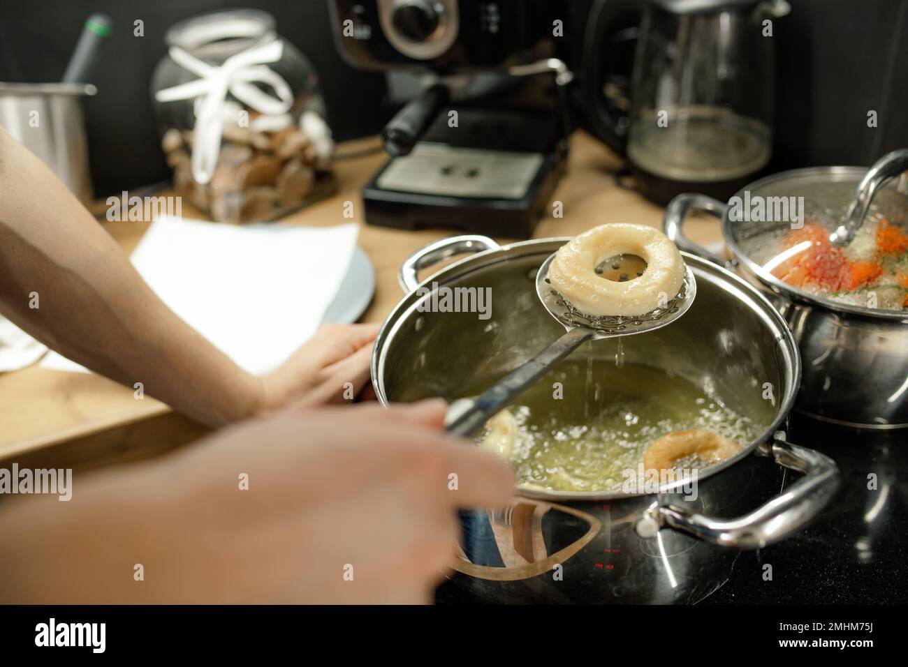 Deep fry dough donuts closeup. Take out ready bagels with slotted spoon