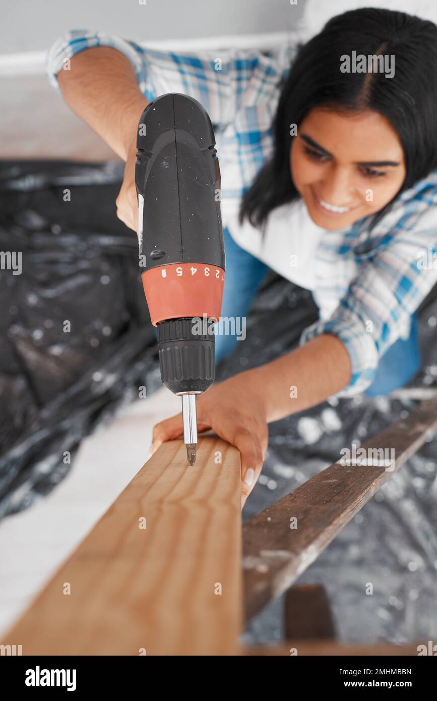 Selective focus on drill with young Indian woman drills into wood