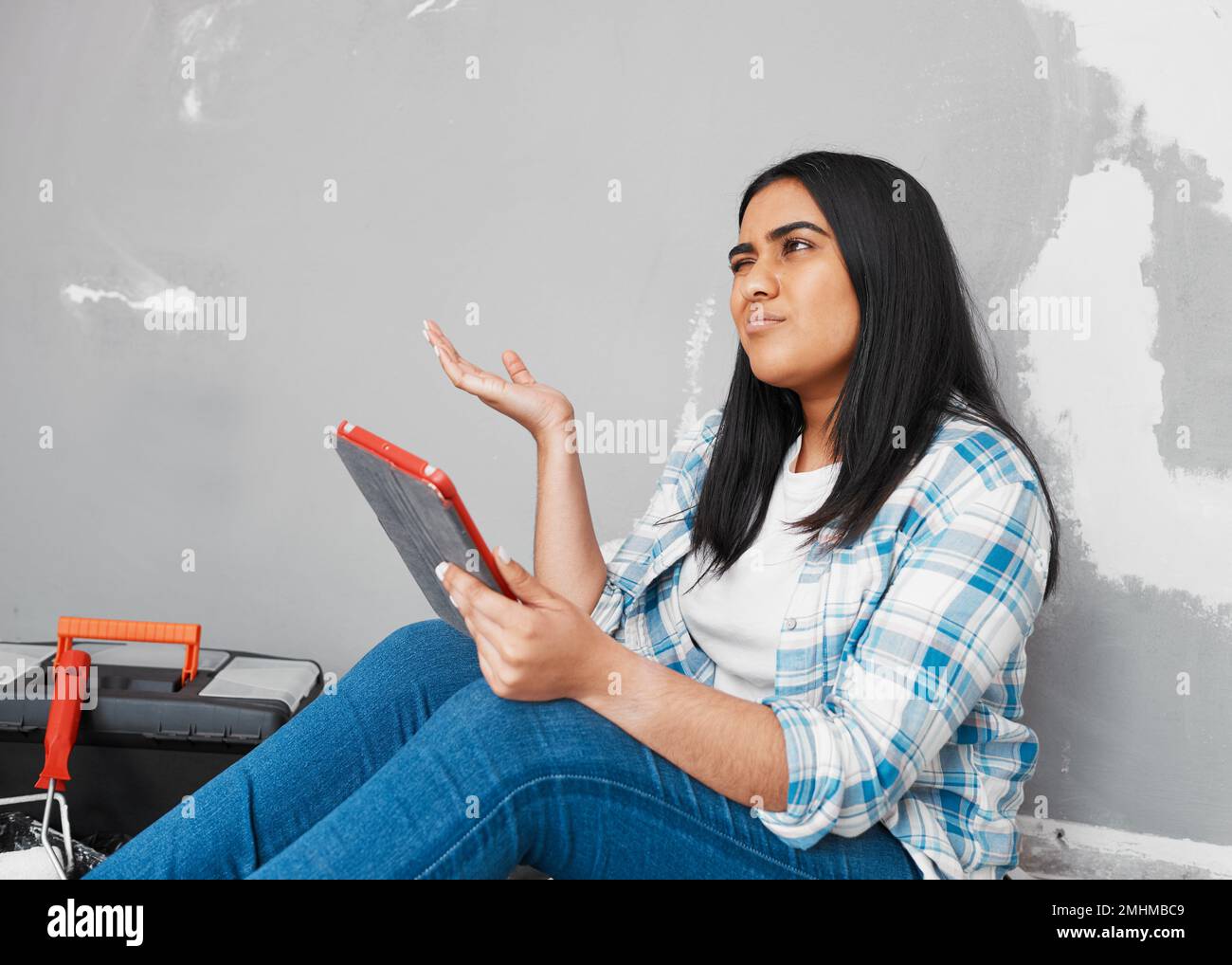 Young Indian woman frustrated, stuck with home DIY project digital how-to guide Stock Photo
