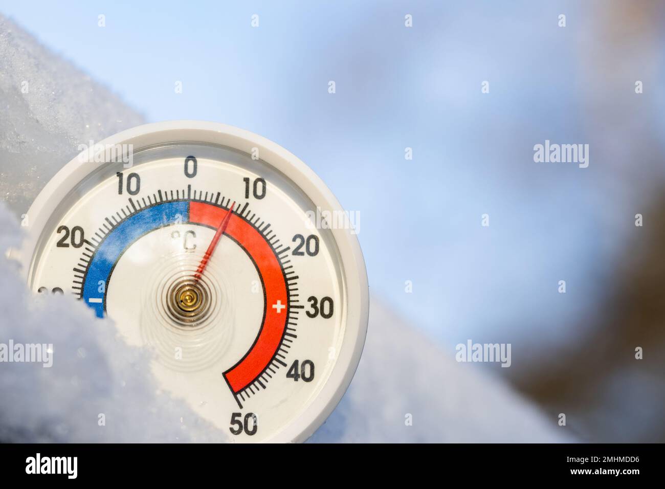 Thermometer with celsius scale in the snow showing plus 8 degree ambient temperature. Unusually high winter conditions. Warm winter weather and climat Stock Photo