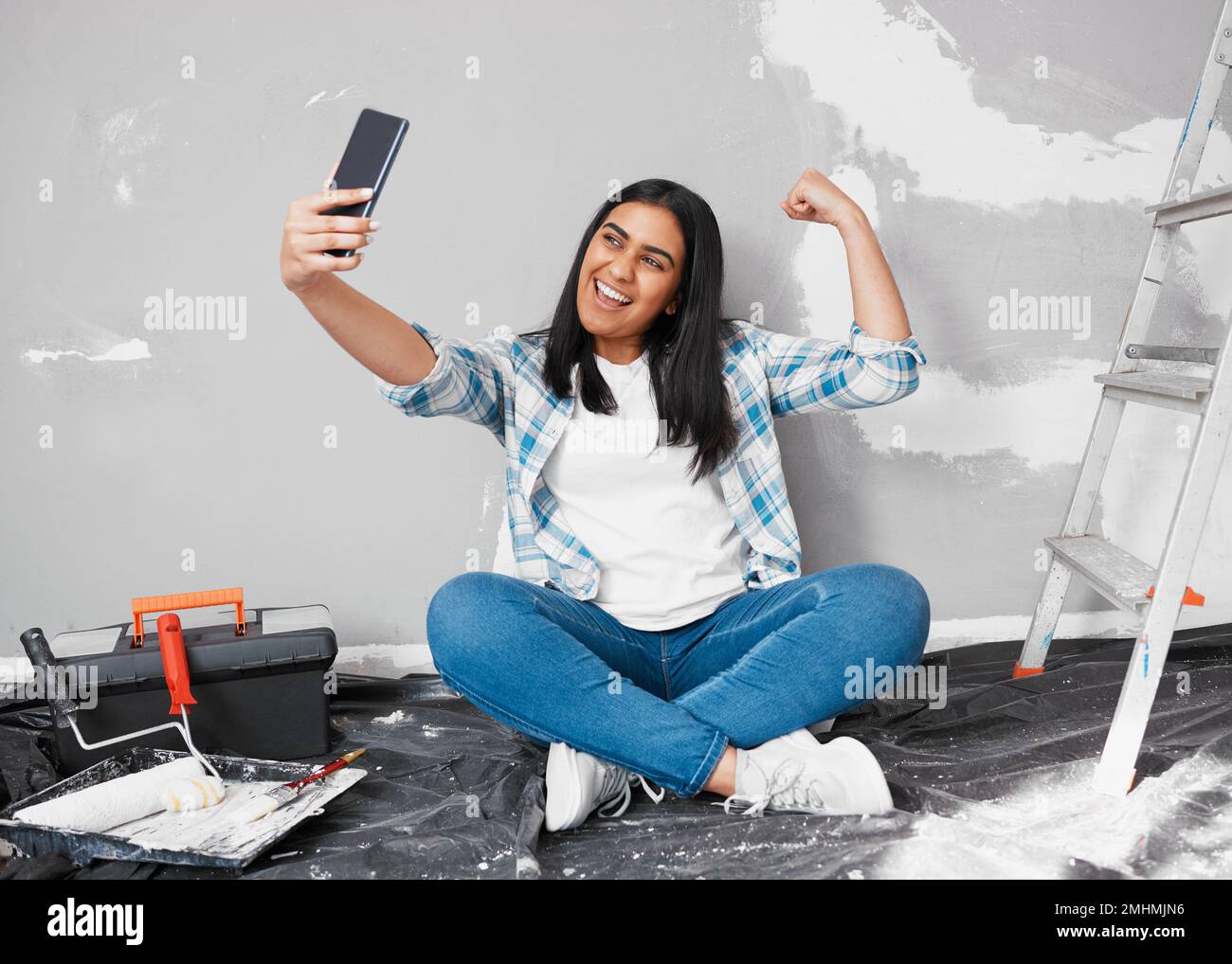 A young Indian woman takes a selfie while busy with home improvement DIY project Stock Photo