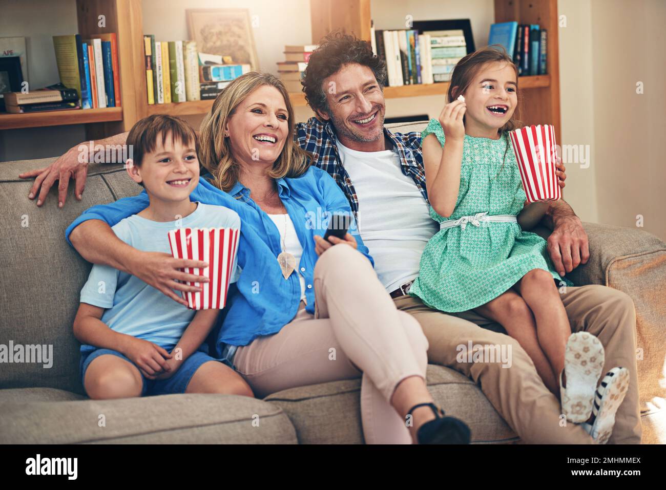 Who needs a cinema when theres a family sized sofa. a happy family watching movies on the sofa at home. Stock Photo