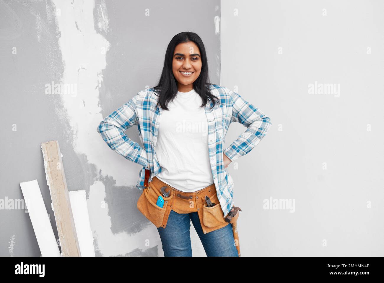 Portrait of a strong young Indian woman about to do DIY at home with tool belt Stock Photo