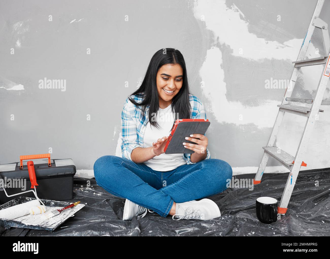 A young woman researches home DIY ideas and how-to guides while renovating Stock Photo