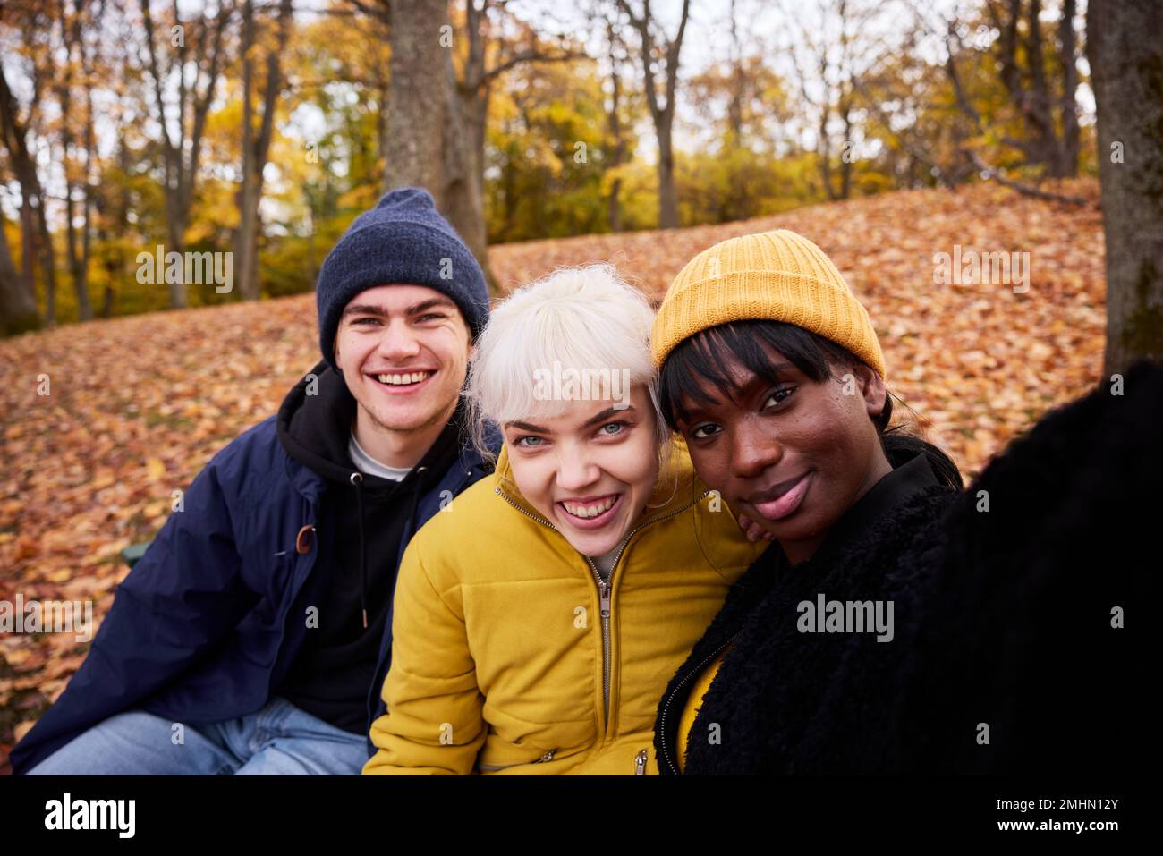 Three friends in park in autumn scenery Stock Photo