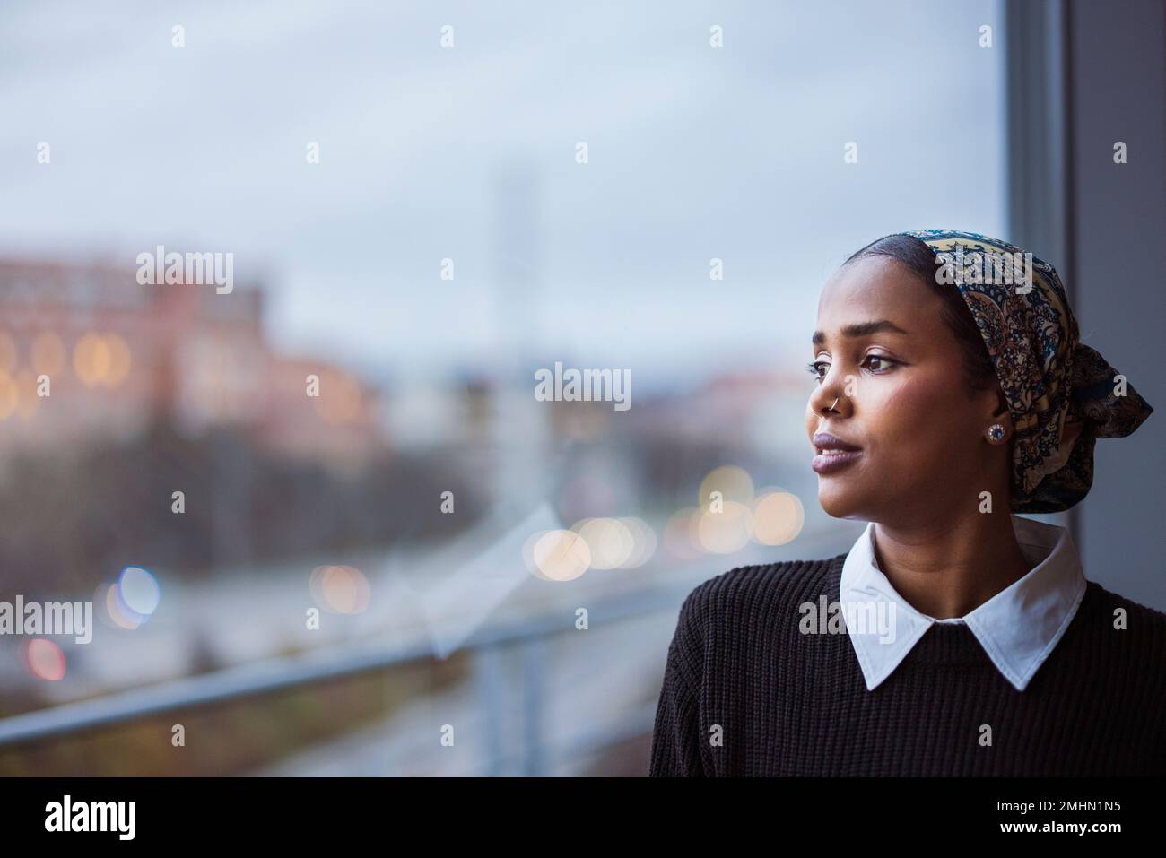 Young woman looking through window Stock Photo