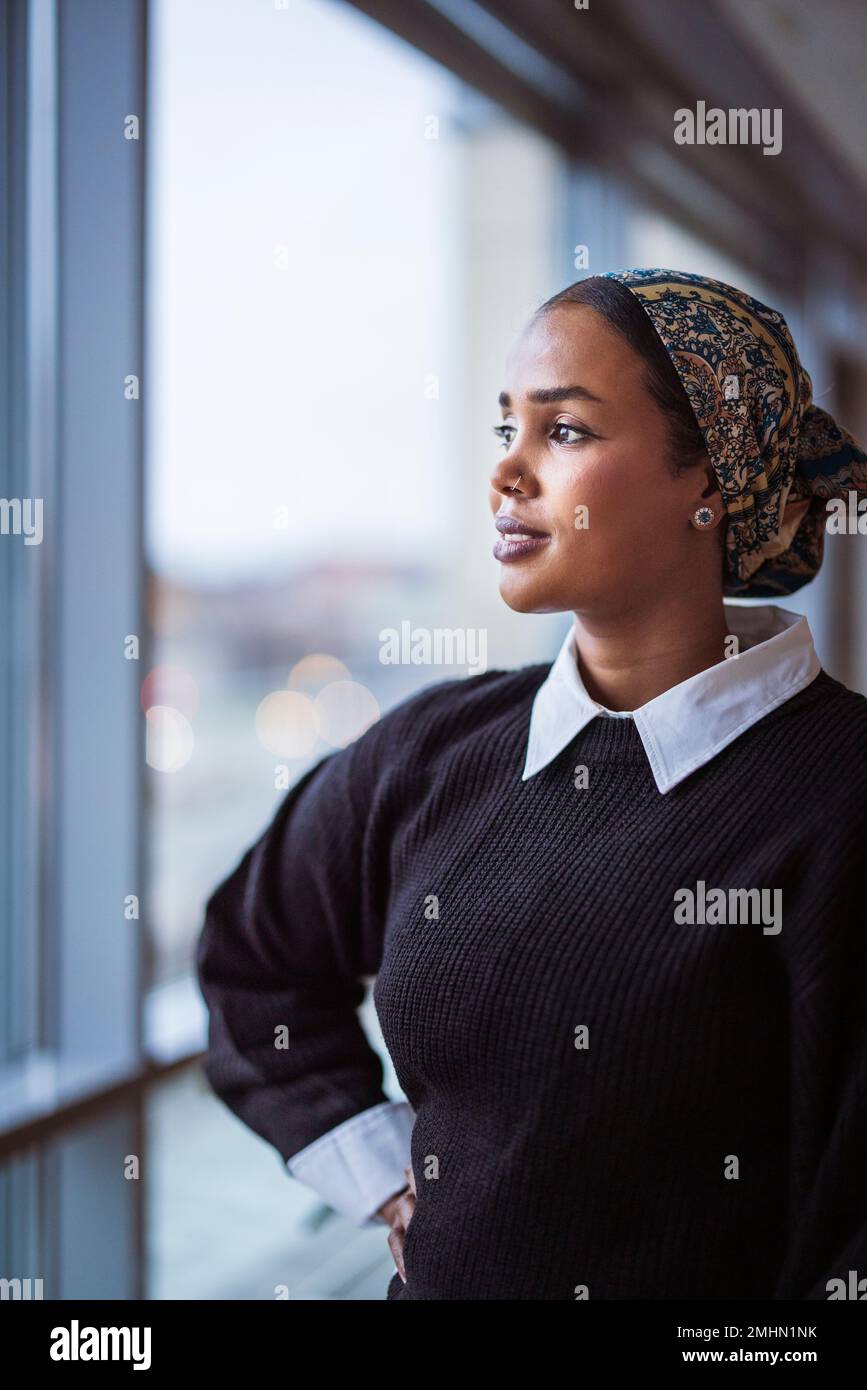 Young woman looking through window Stock Photo