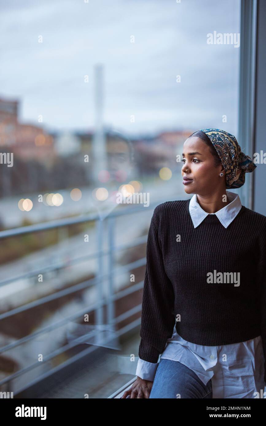 Young woman looking through window Stock Photo