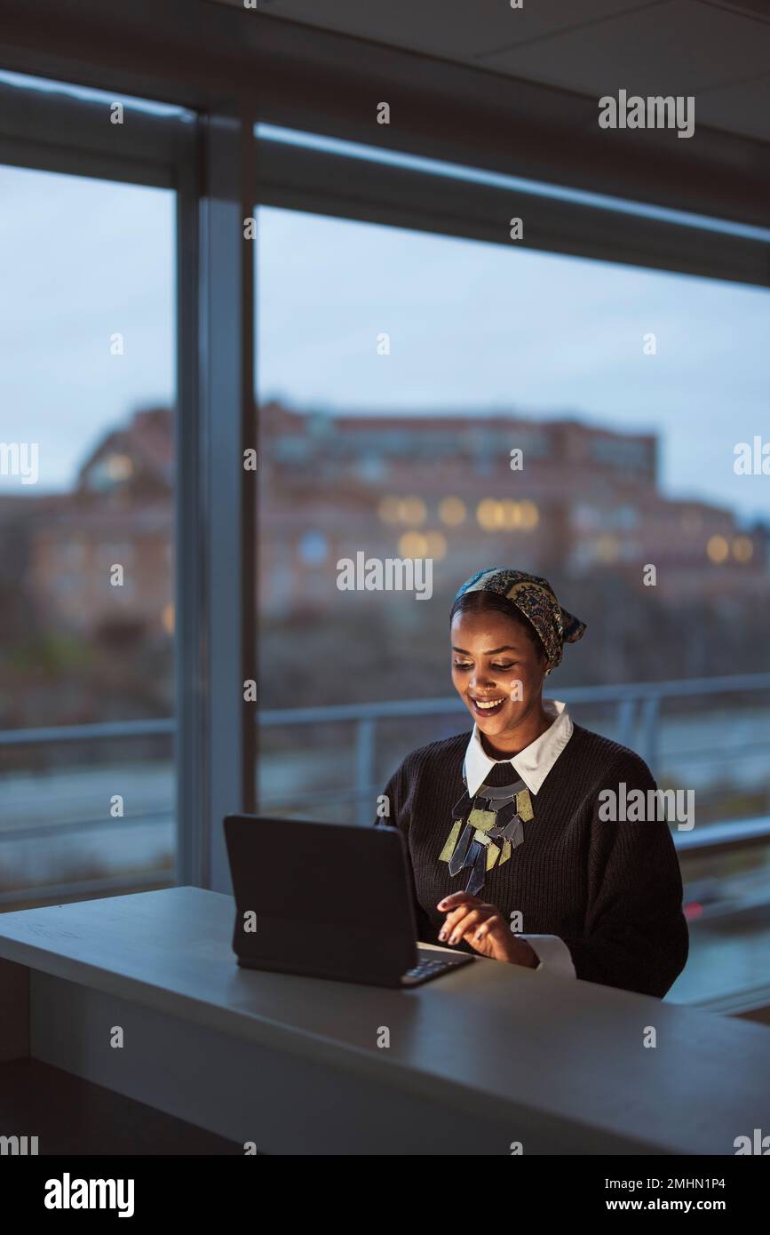 Smiling young woman working on laptop Stock Photo